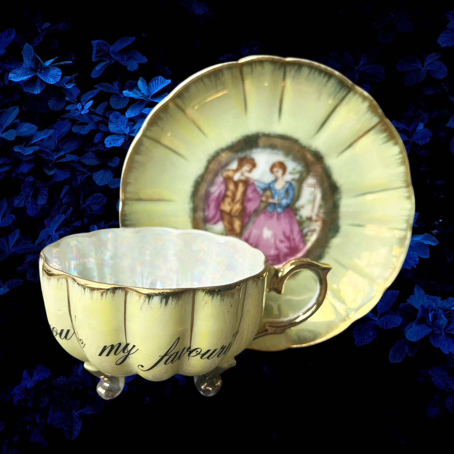 A yellow scalloped shaped tea cup with a picture of a couple and the words "In a world full of cunts you're my favourite"