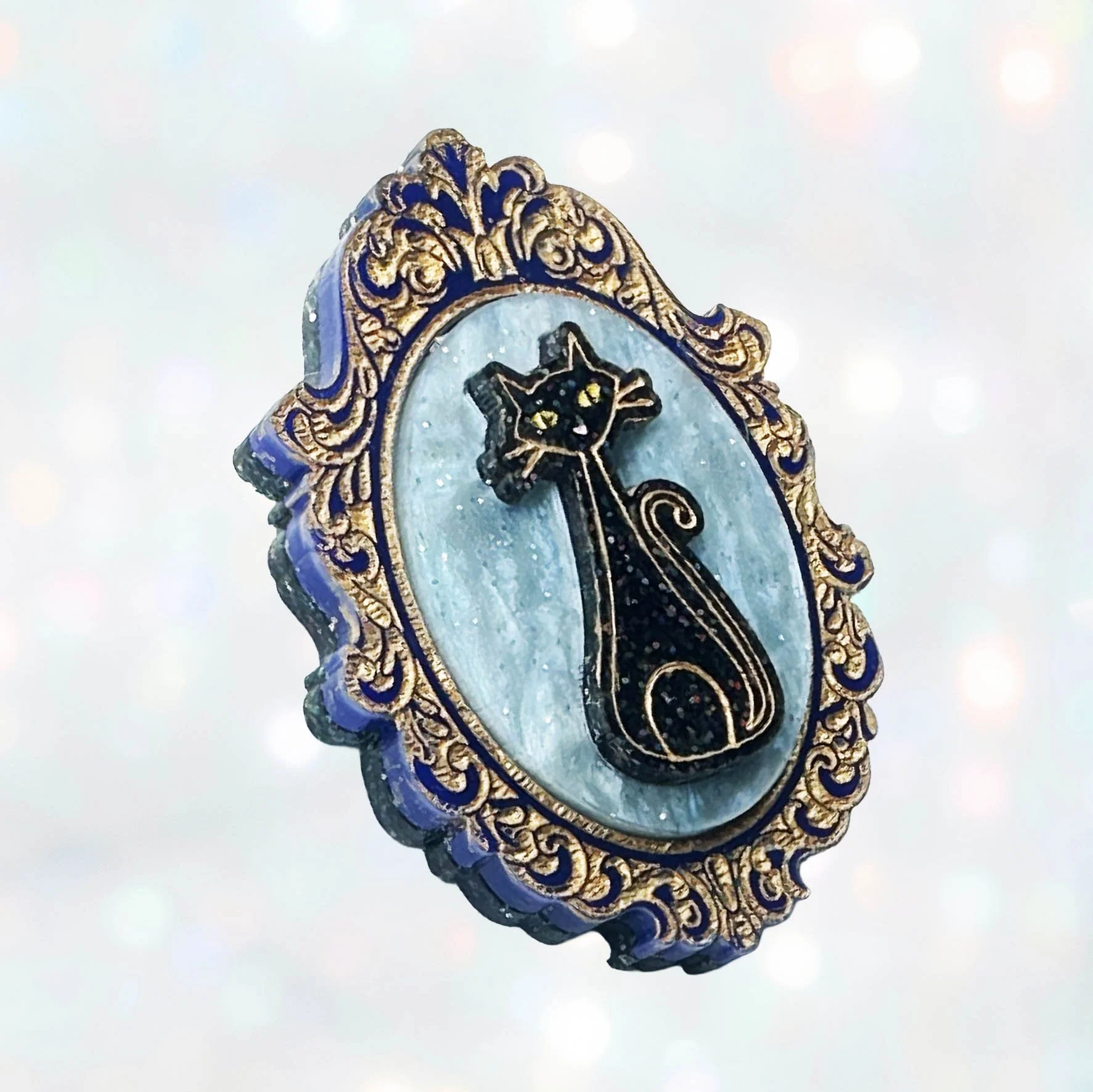 Laser cut acrylic cameo style brooch featuring black cats inside gold frames