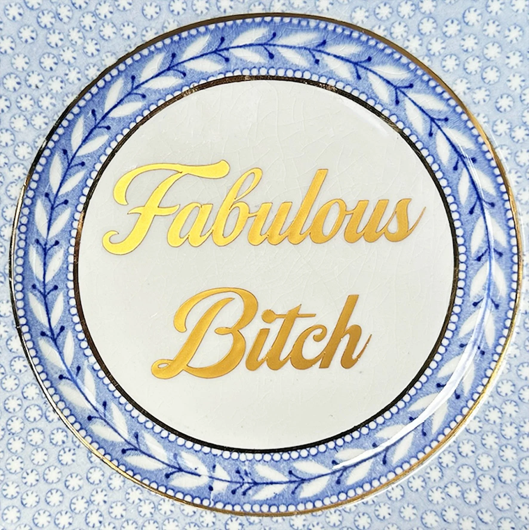 a blue vintage plate with the quote "fabulous bitch" in gold writing