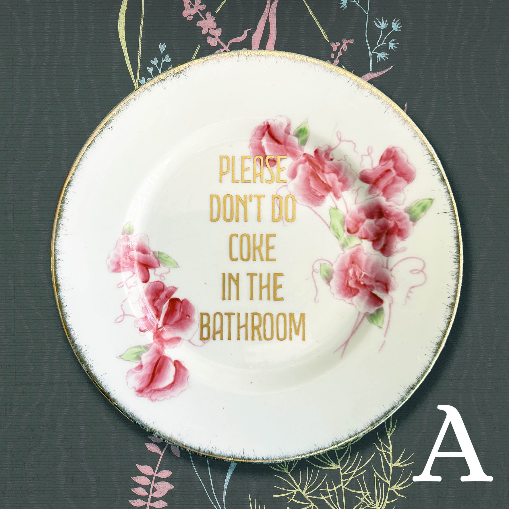 Plate A, a small vintage plate with a pink floral design and a quote "please don't do coke in the bathroom" in gold lettering