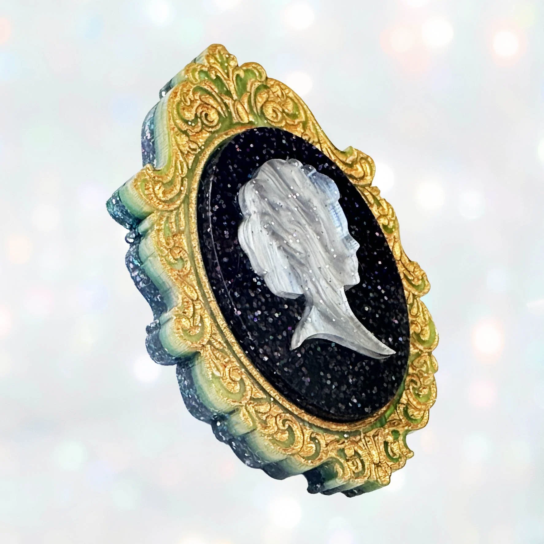 A laser cut green gold and black acrylic cameo style brooch featuring a silhouette