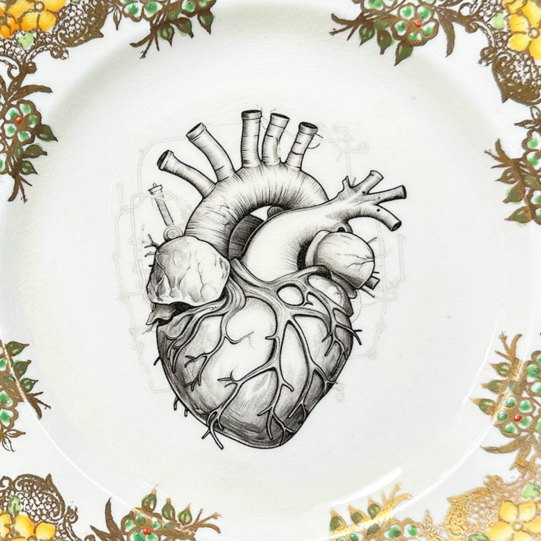 A cream and gold vintage plate with a picture of an anatomical heart