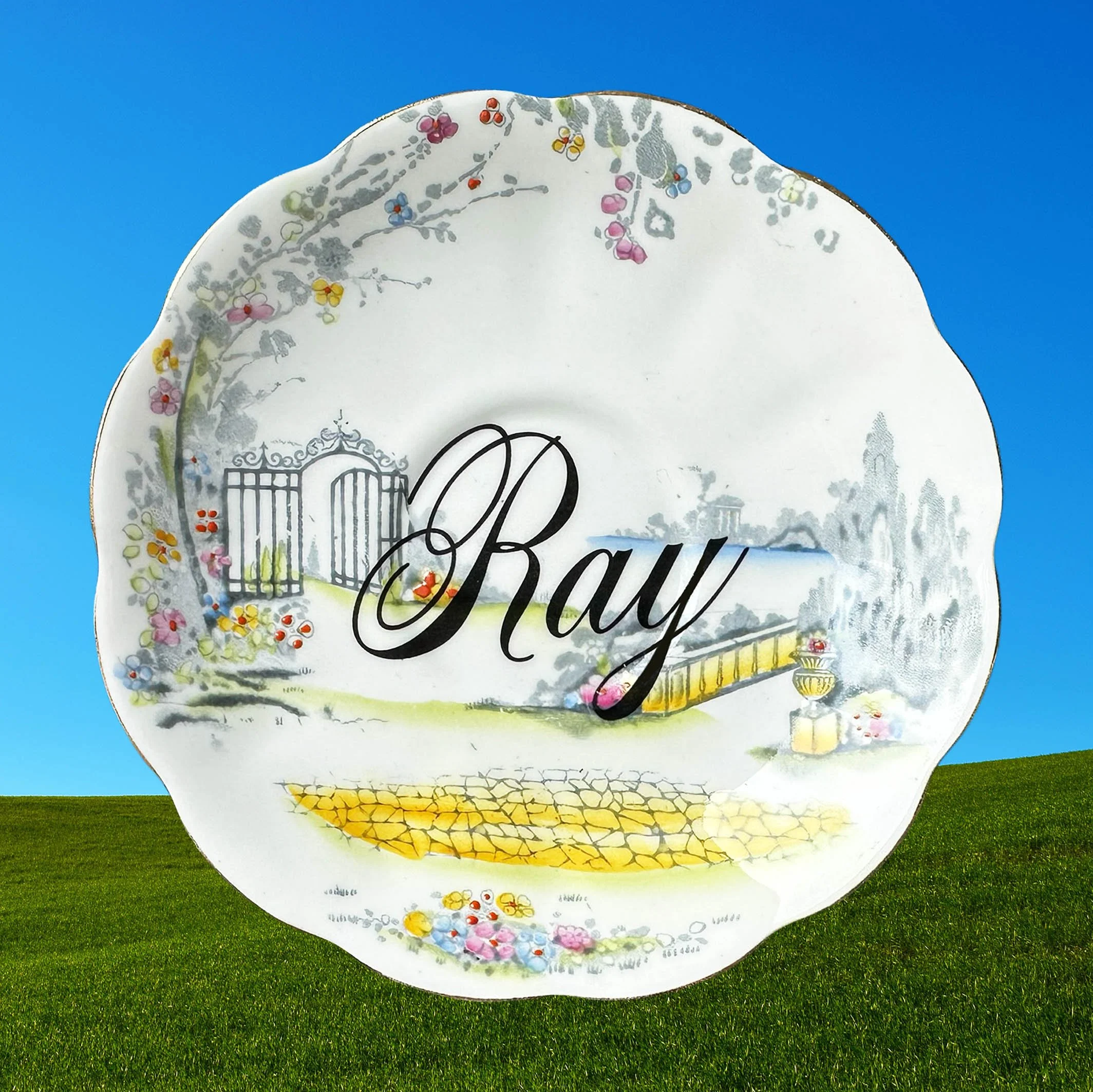 Saucer 1 featuring the word ray in black cursive writing on a Royal Albert saucer with a garden scene