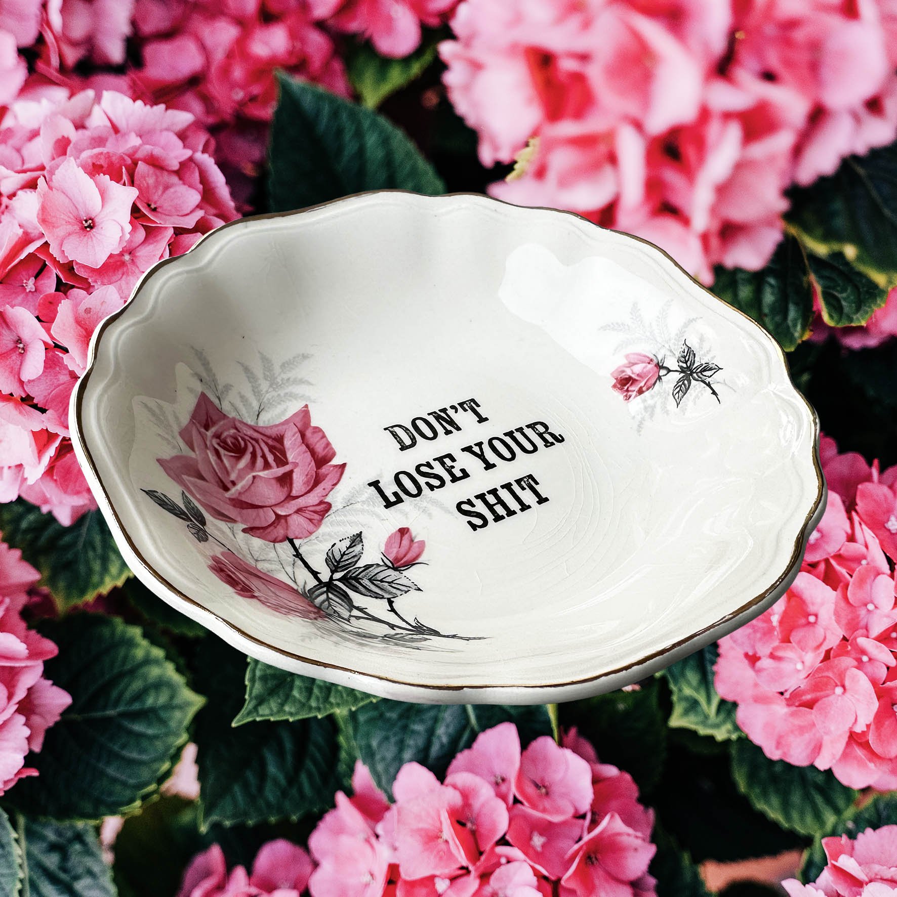 A vintage trinket dish with a pink floral design and the words “don’t lose your shit”