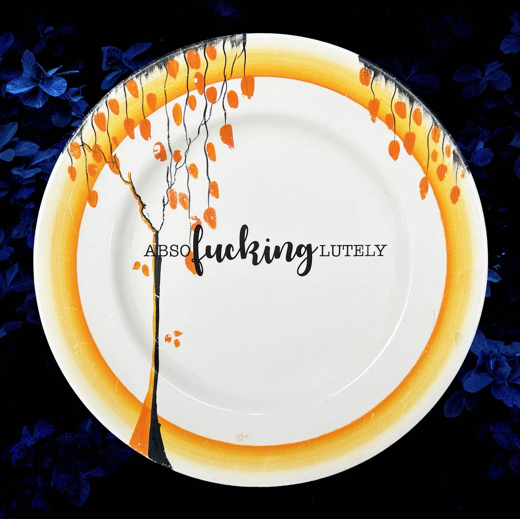 A vintage plate with an orange tree design and the word “absofuckinglutely”