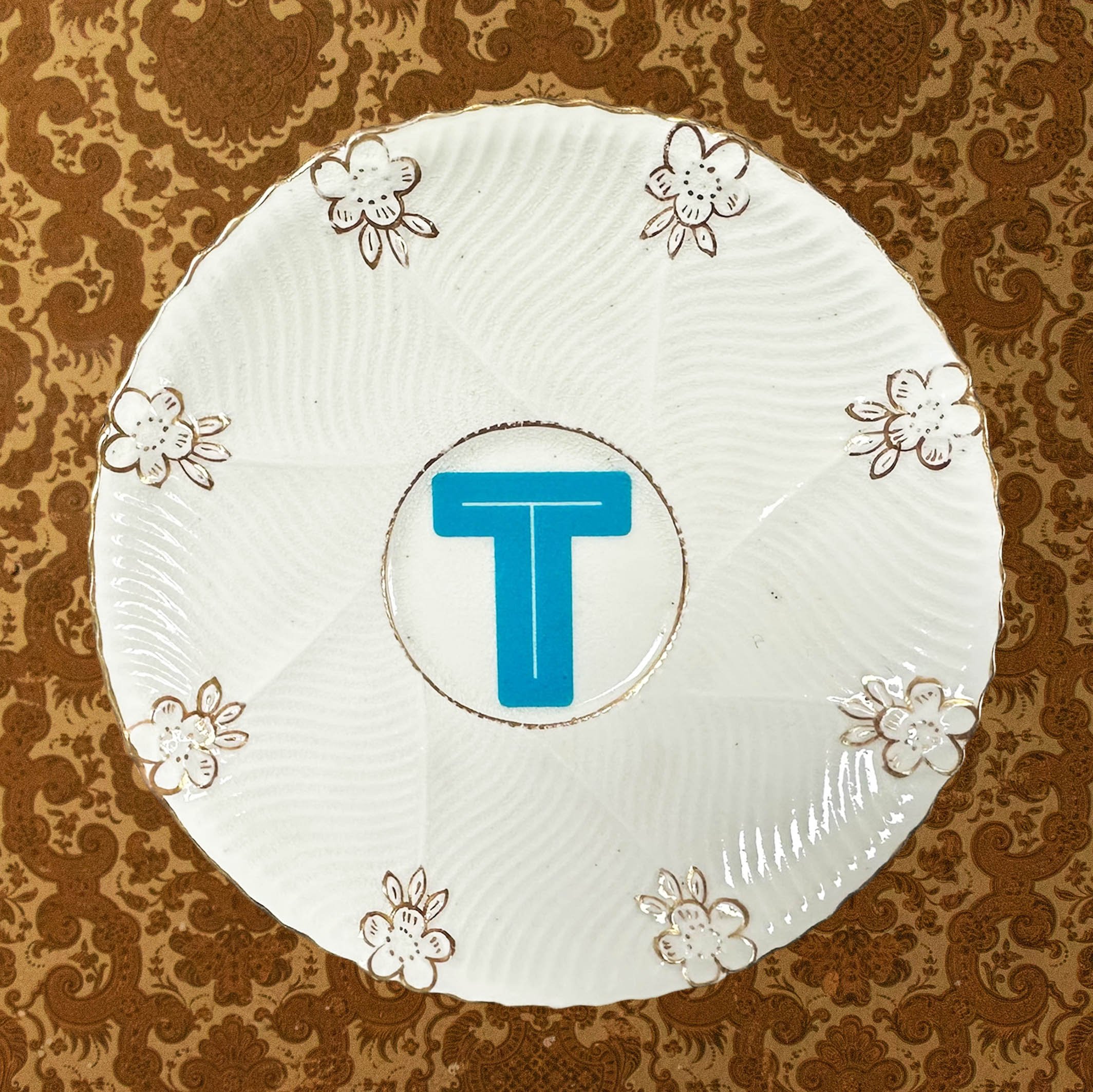 Saucer 4 featuring the letter T in blue in a vintage saucer with small gold flowers
