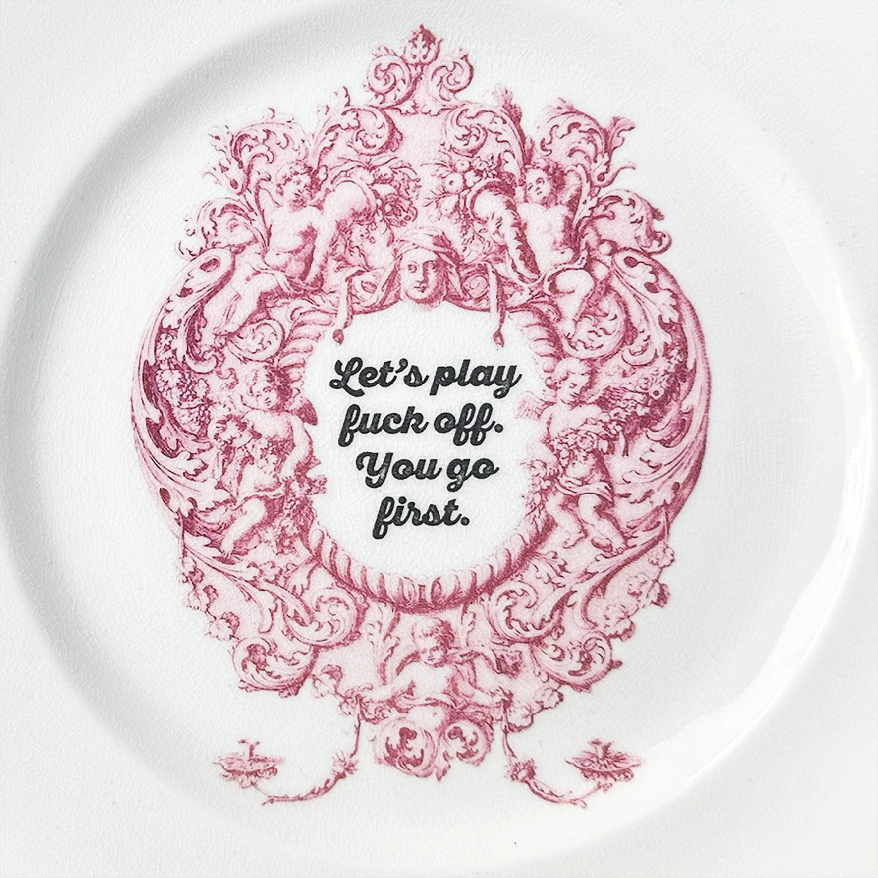 Plate B, a small vintage plate with an ornate pink frame with the words “let’s play fuck off. You go first”