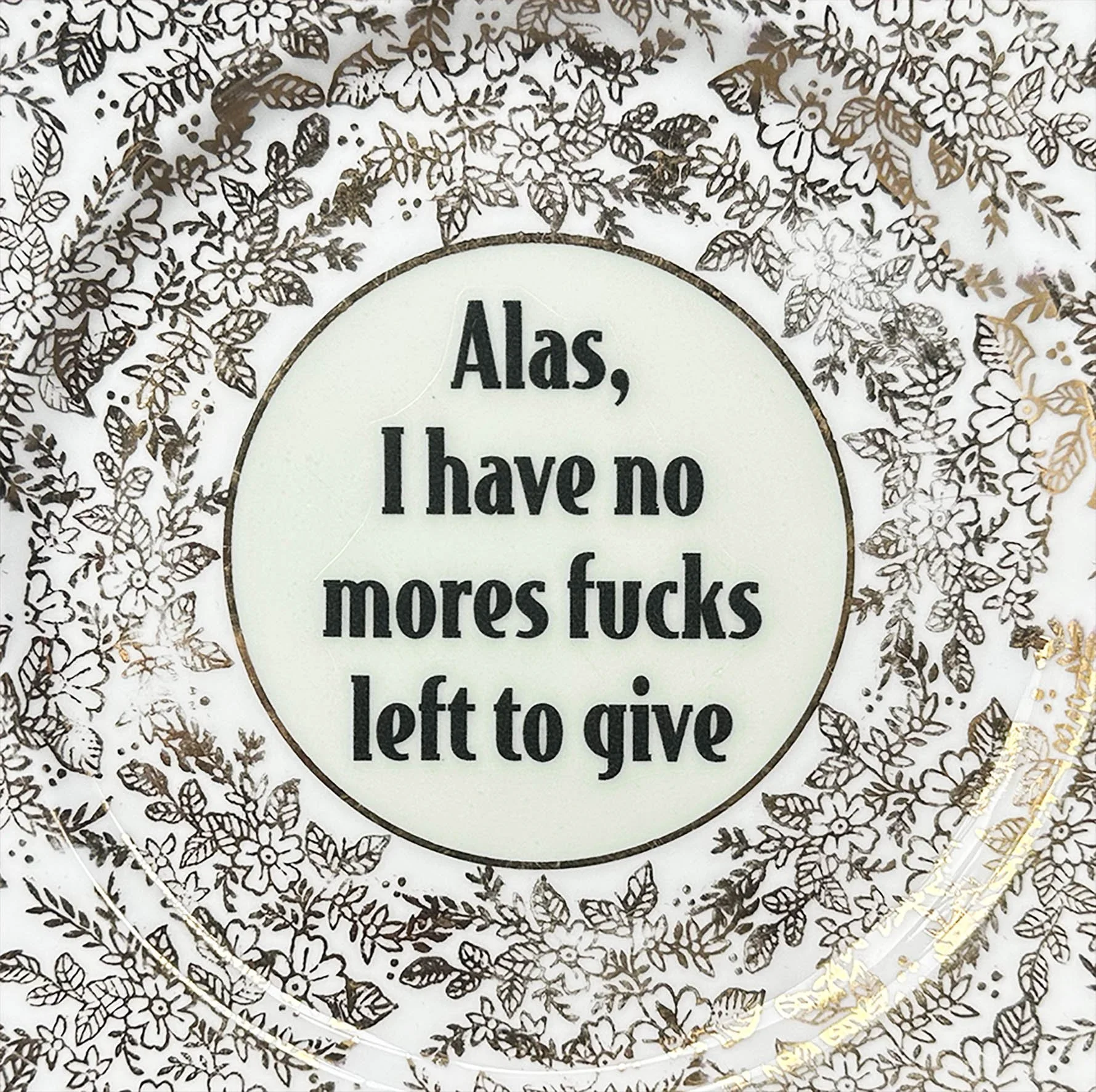 Vintage decorative plate with a green and gold floral design and the words “alas, I have no more fucks left to give” in black writing
