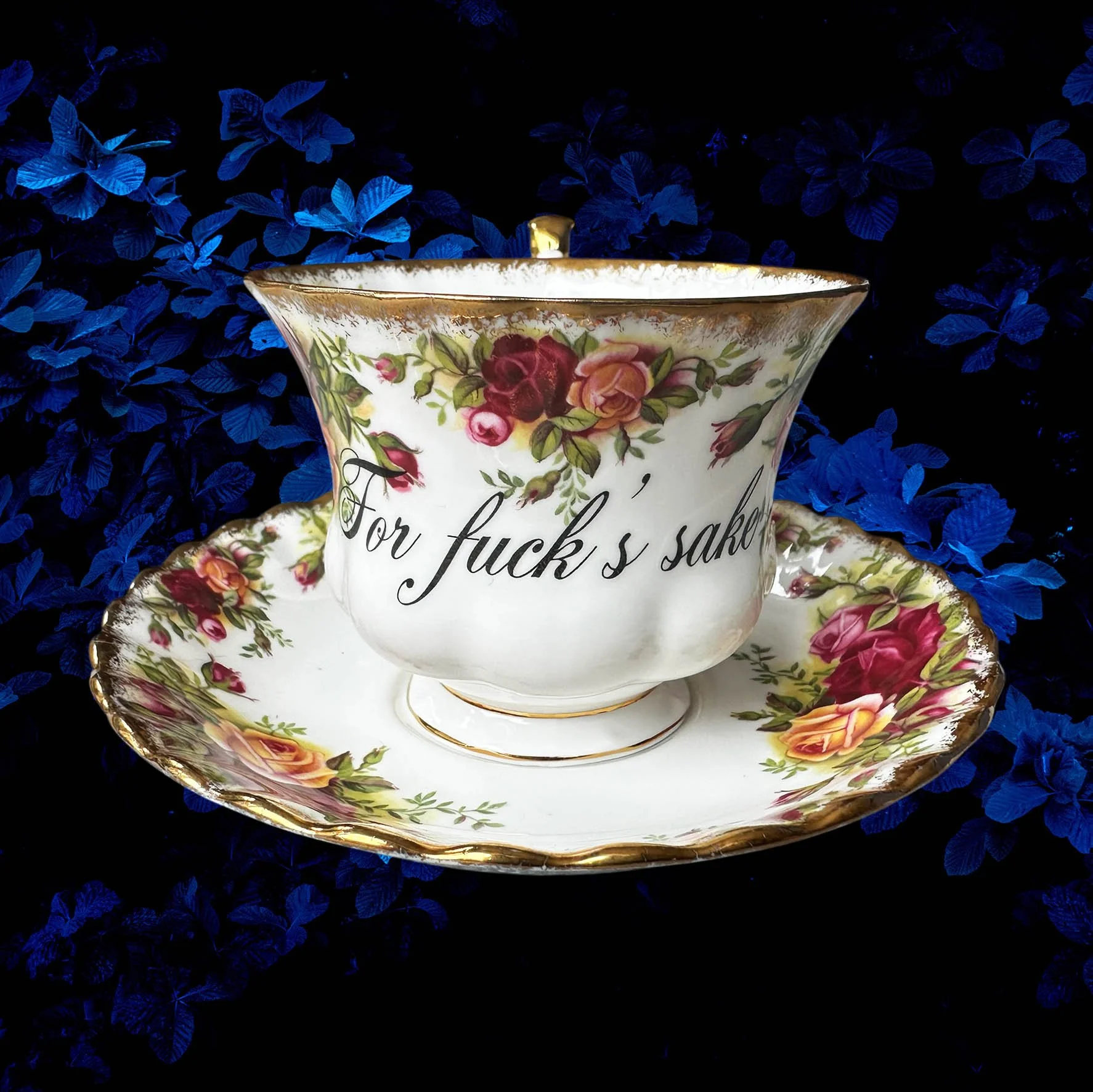 a vintage tea cup with a red rose design and the words "for fuck's sake" in black writing