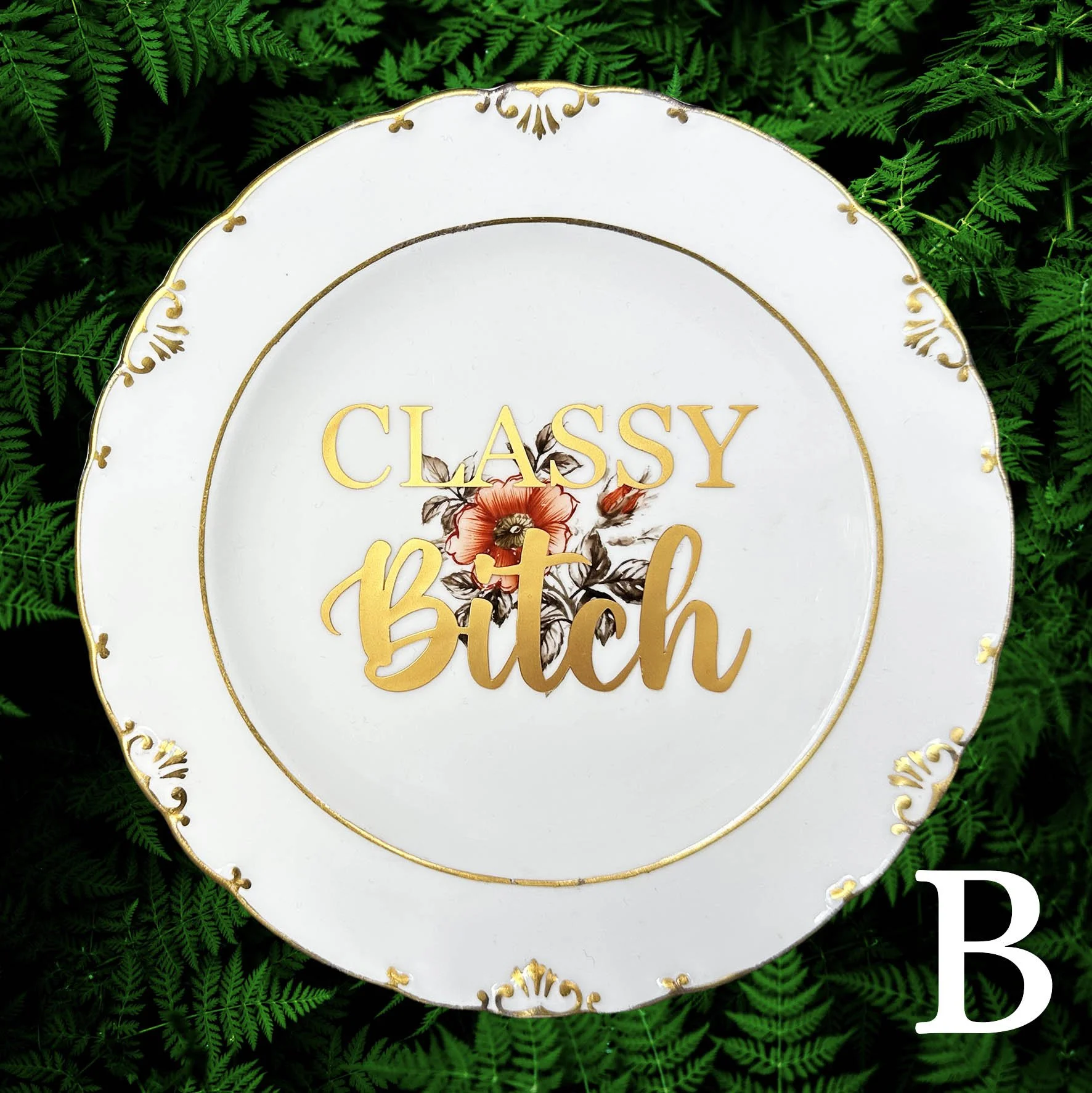 A vintage plate with a witty quote “classy bitch” in gold writing