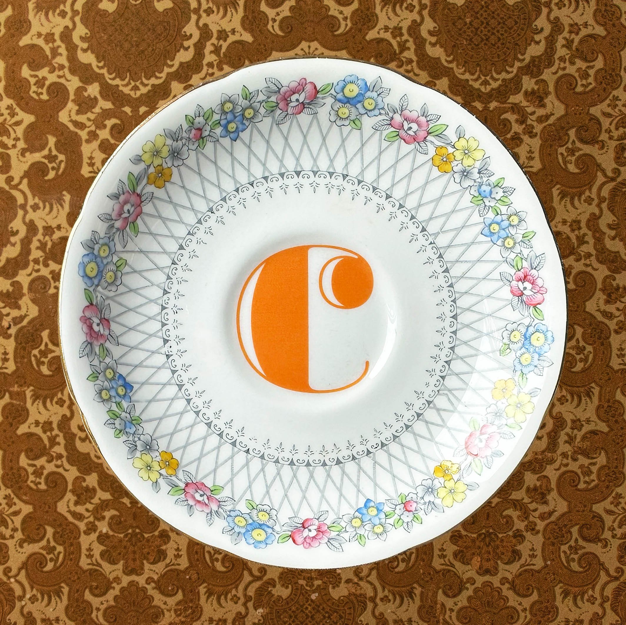 Saucer 1, the lettering is heat C coloured orange on a vintage saucer with a blue border