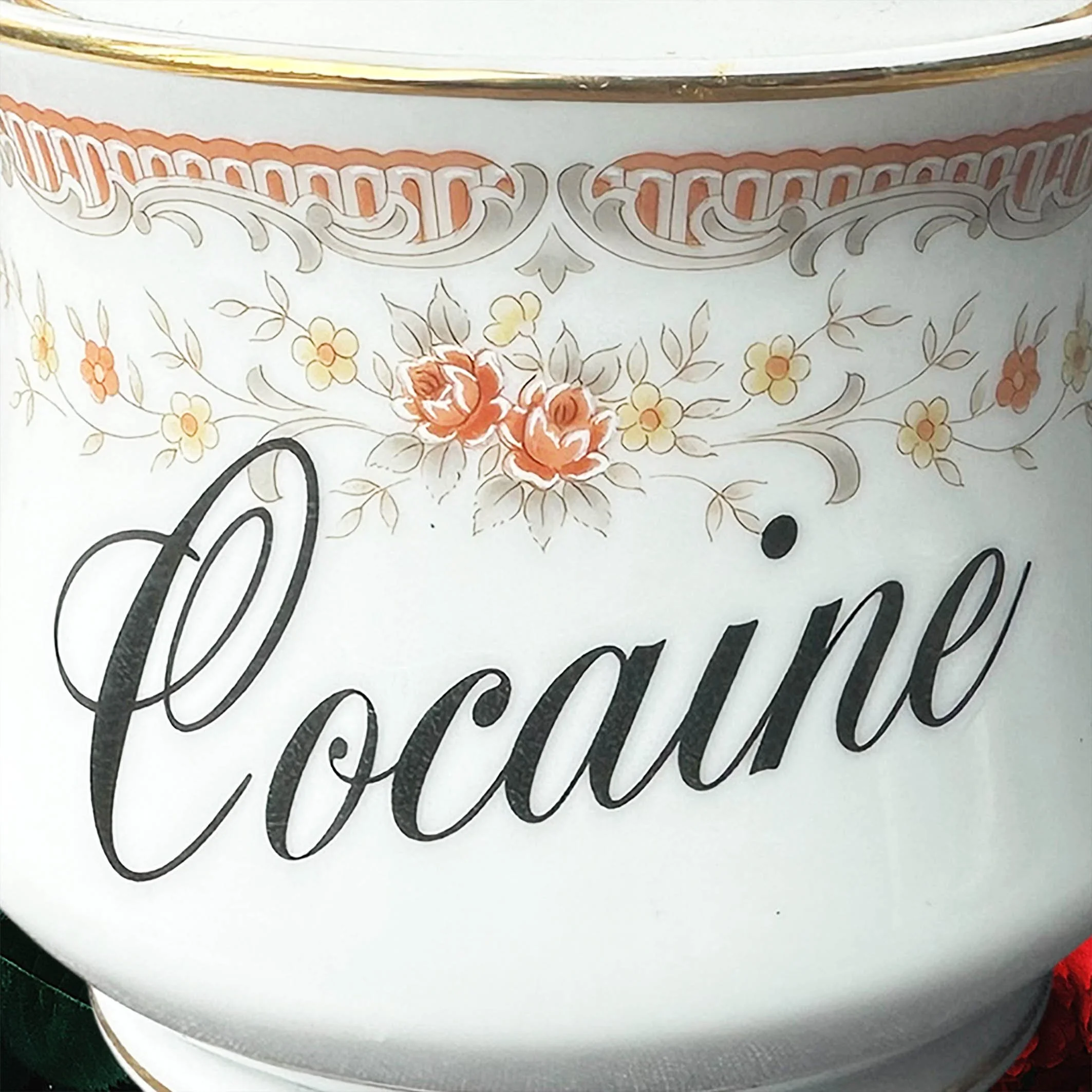 A vintage Japanese sugar bowl with a peach coloured floral design and the words “cocaine” in black cursive writing