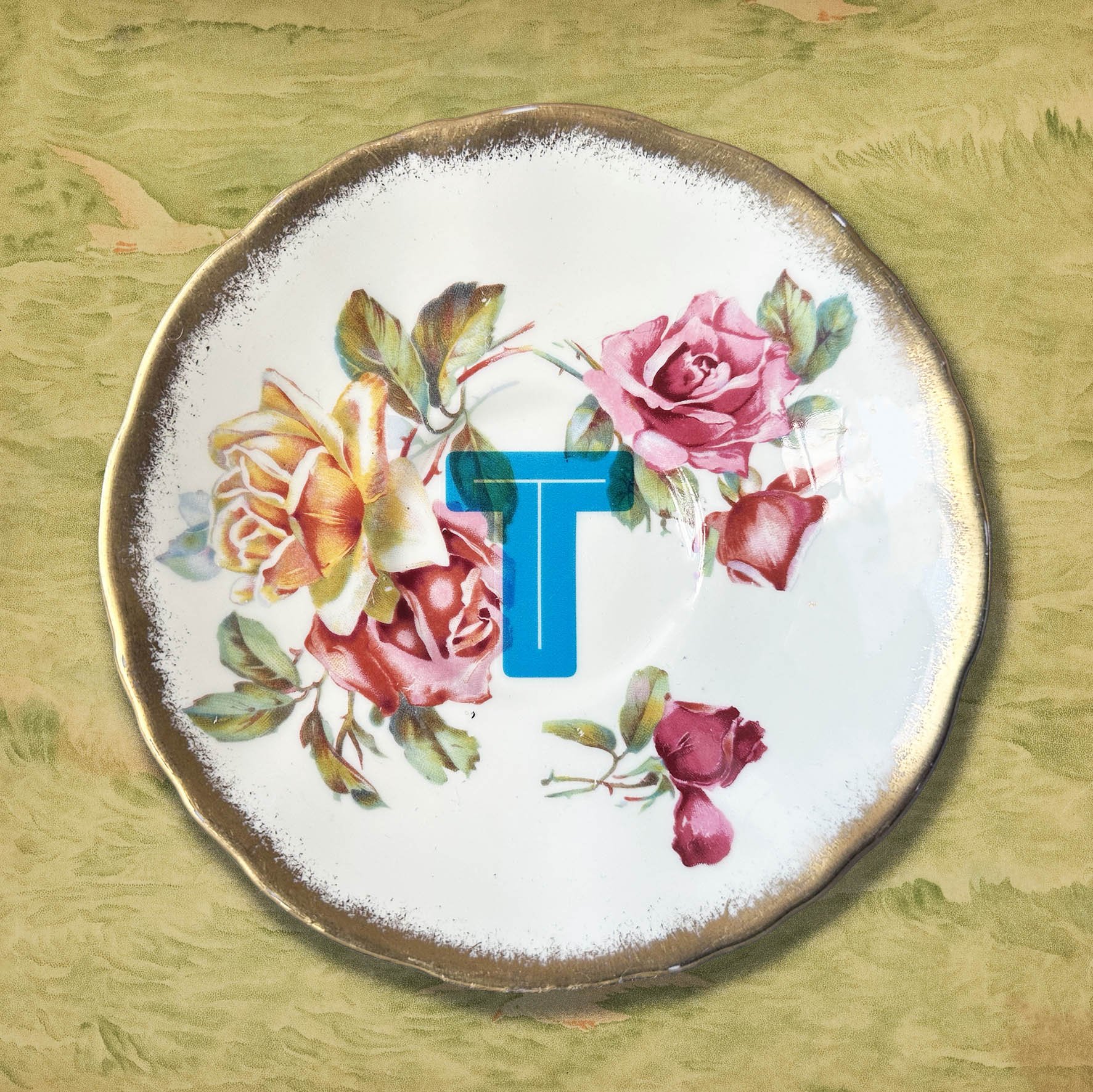A vintage saucer with an orange blue letter T