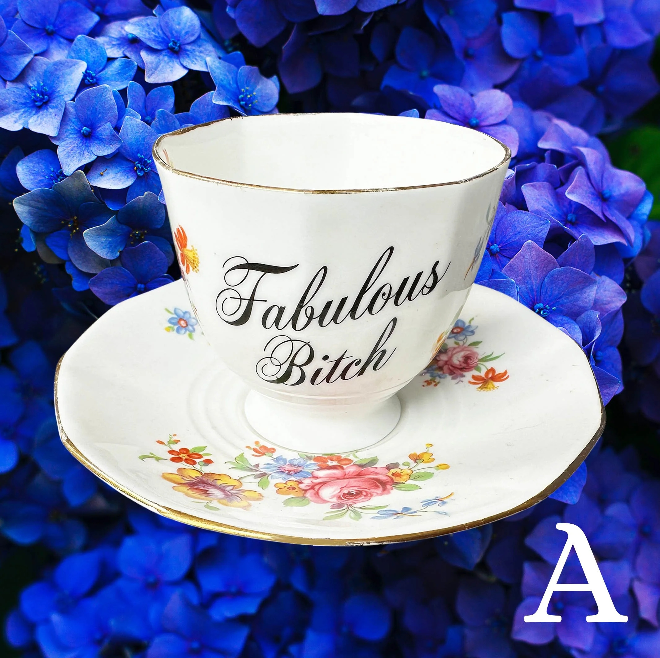 A vintage tea cup with delicate multicoloured flowers and the words “fabulous bitch” in black cursive writing