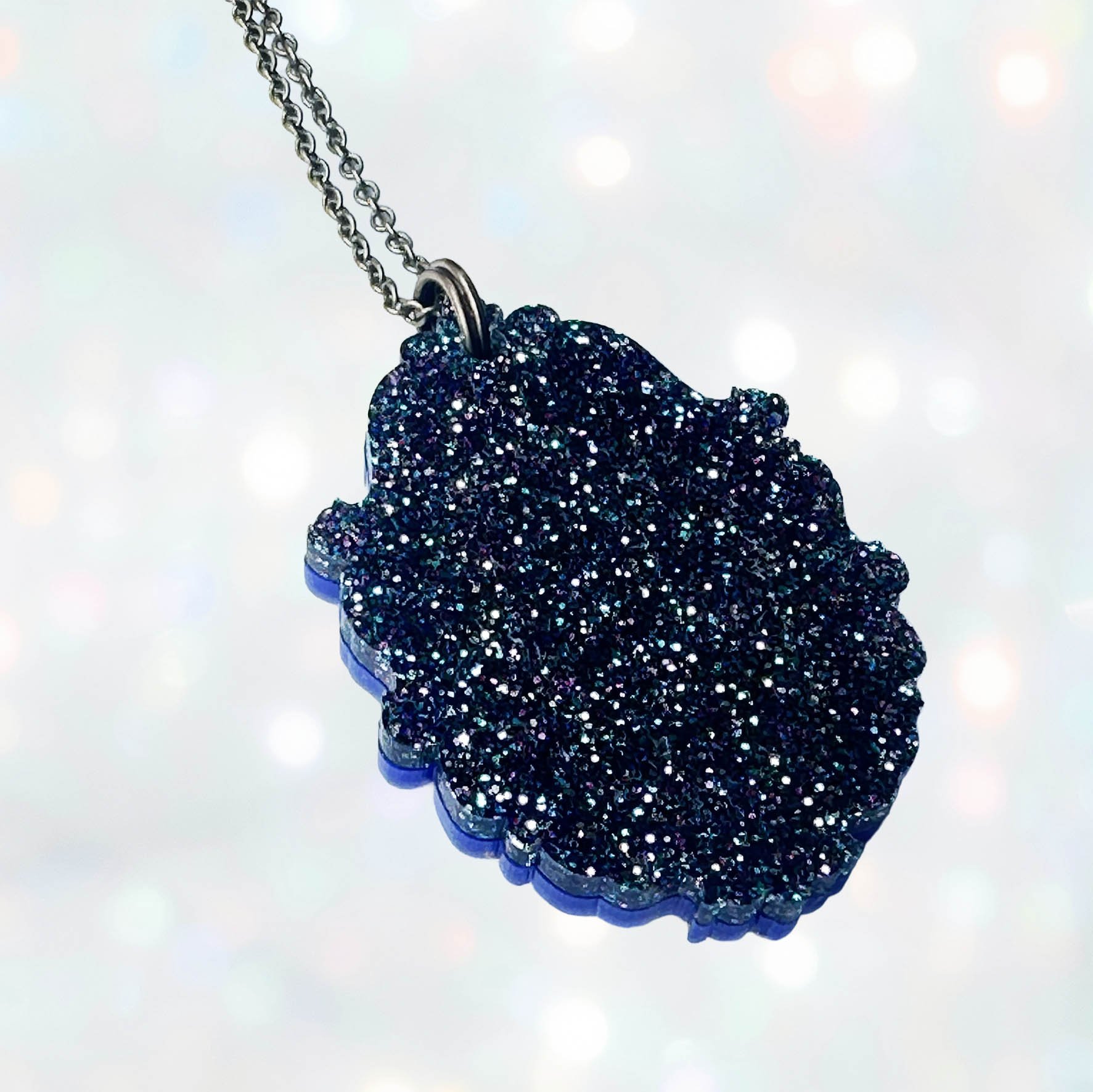 A laser cut acrylic cameo style necklace featuring a black cat inside inside a gold frame
