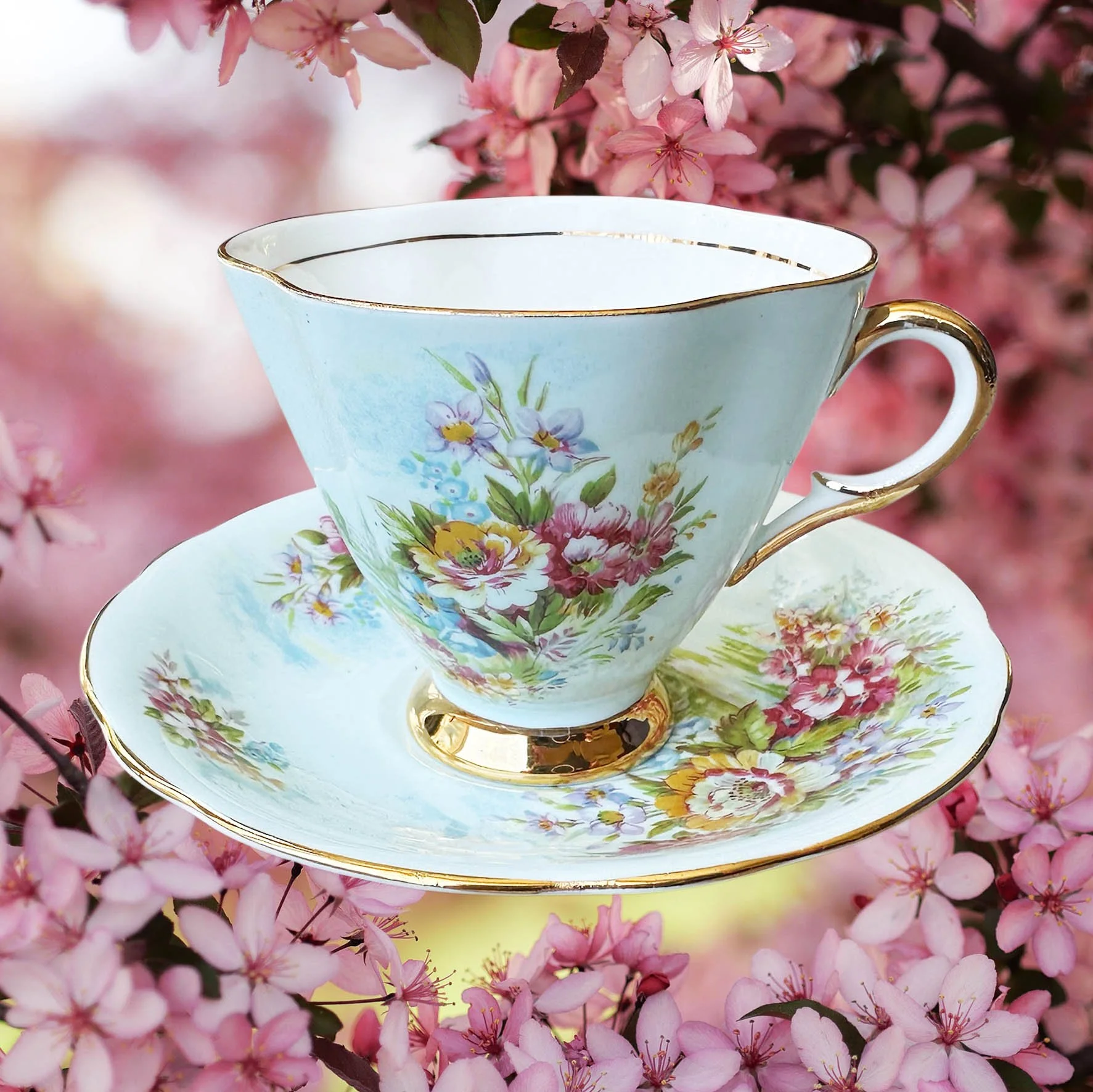 A light blue vintage tea cup and saucer with a blue floral design, with the words "fancy as fuck" in black cursive writing