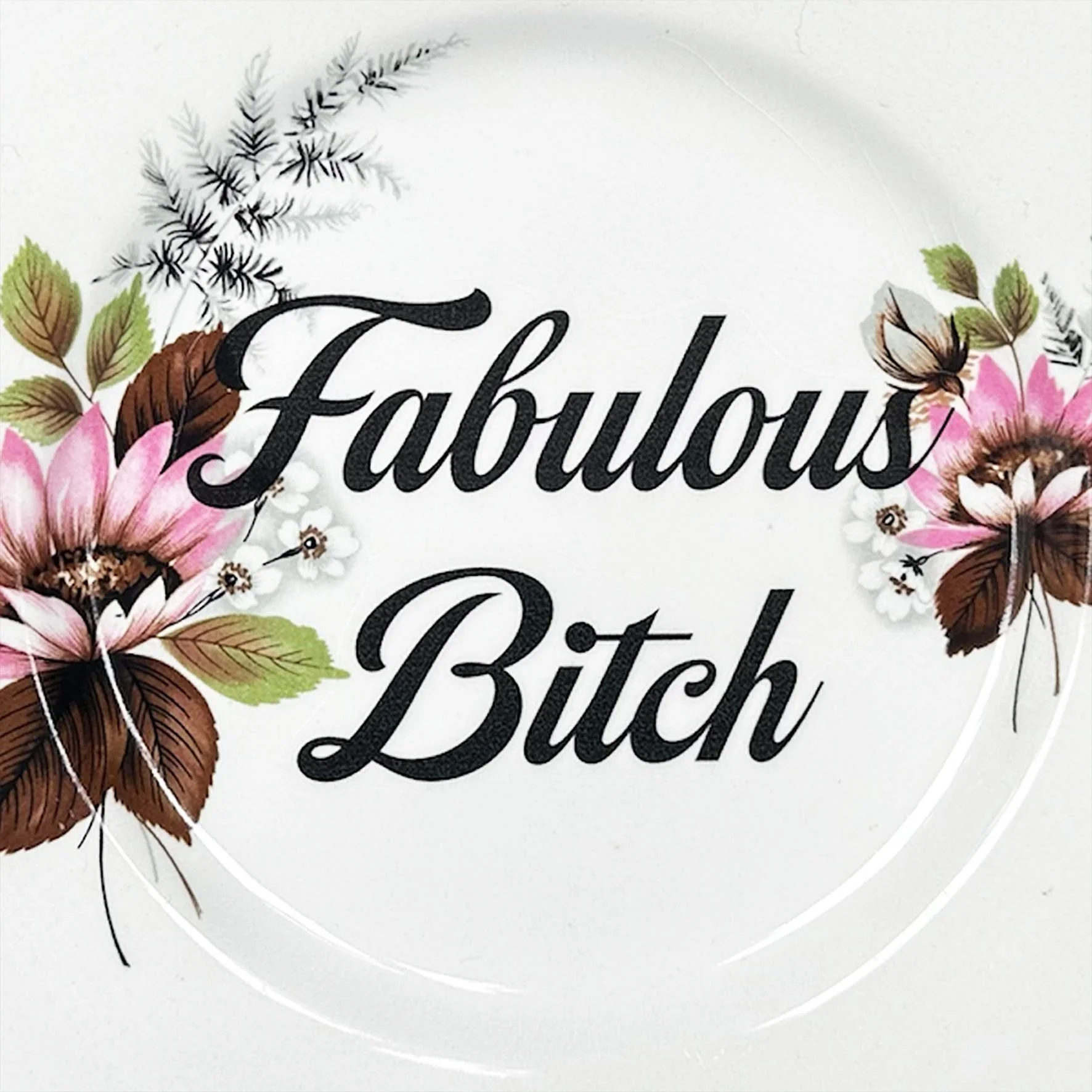 a vintage plate with a pink floral design and the quote "fabulous bitch" in black writing