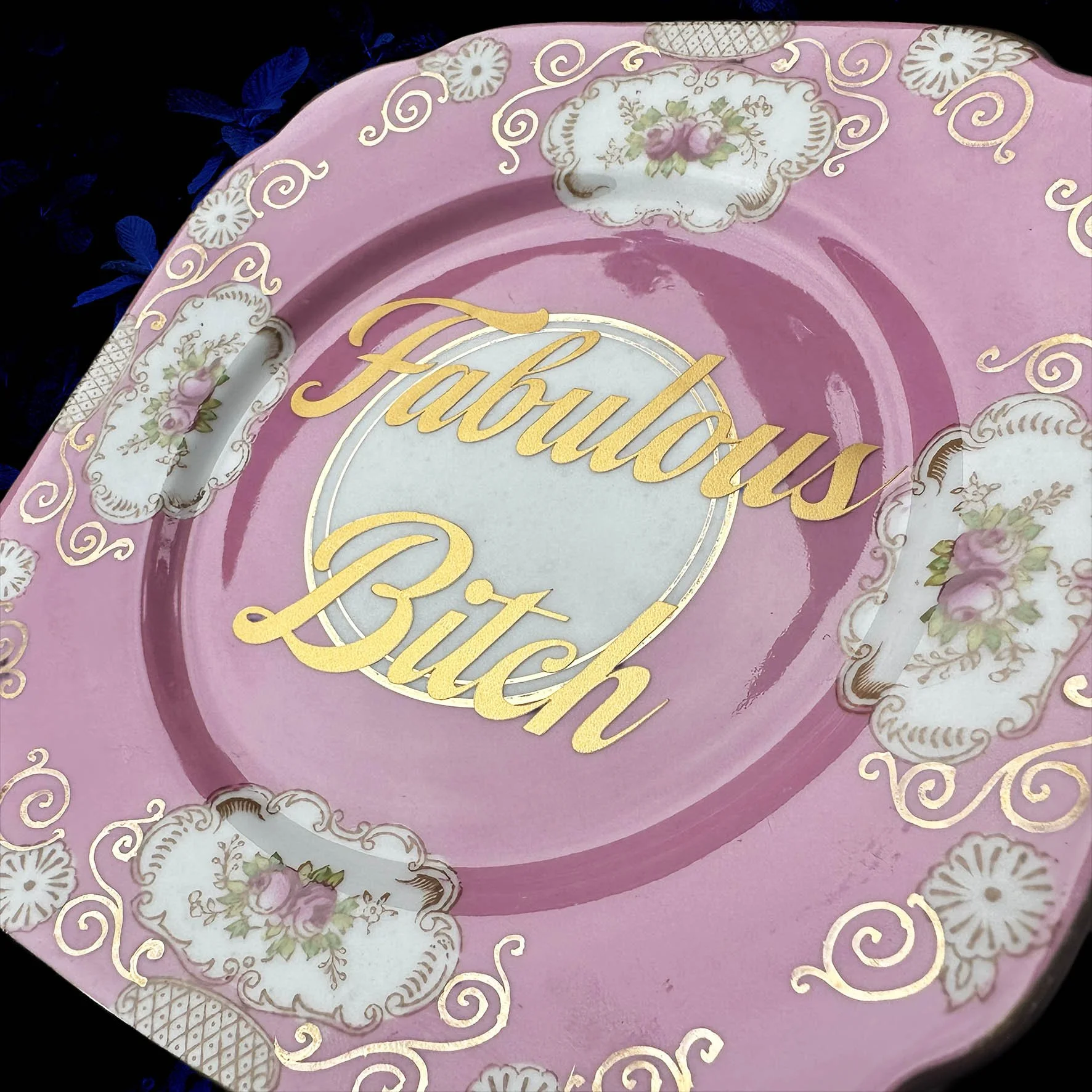Plate B, a pink vintage plate with a floral design and the words "fabulous bitch" in gold writing