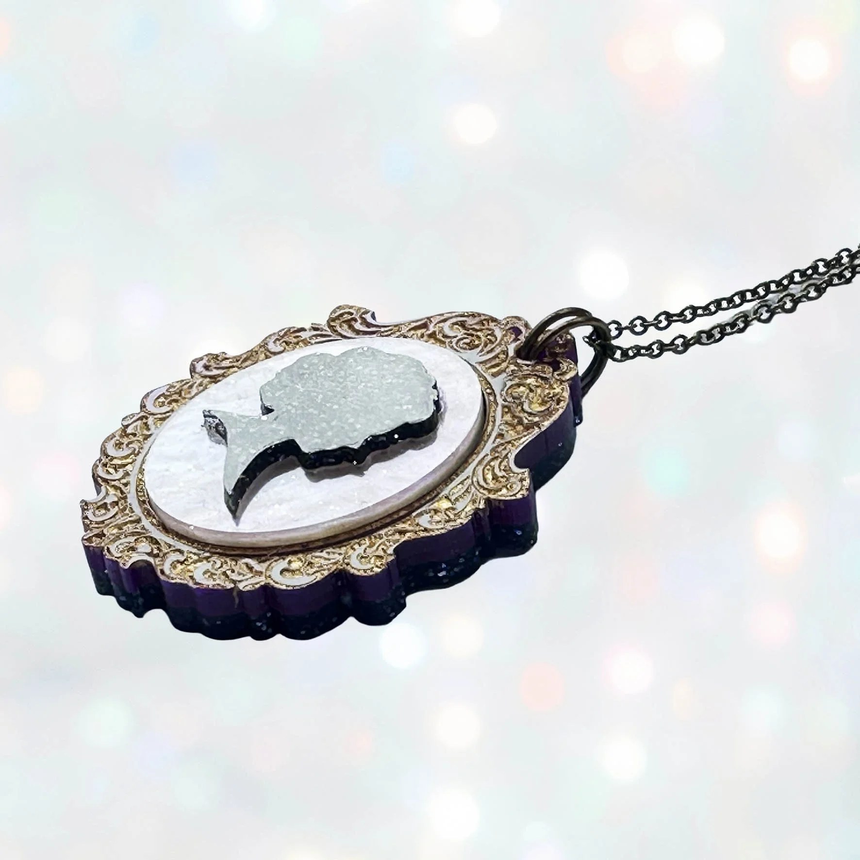 A purple, pink and gold laser cut acrylic cameo style necklace featuring a silhouette