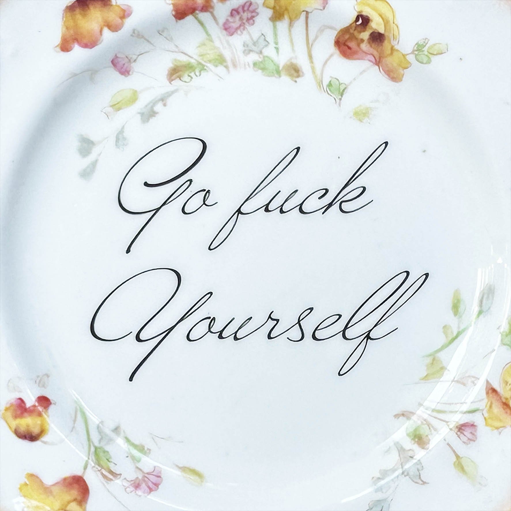 A vintage plate with floral design and the quote “go fuck yourself”