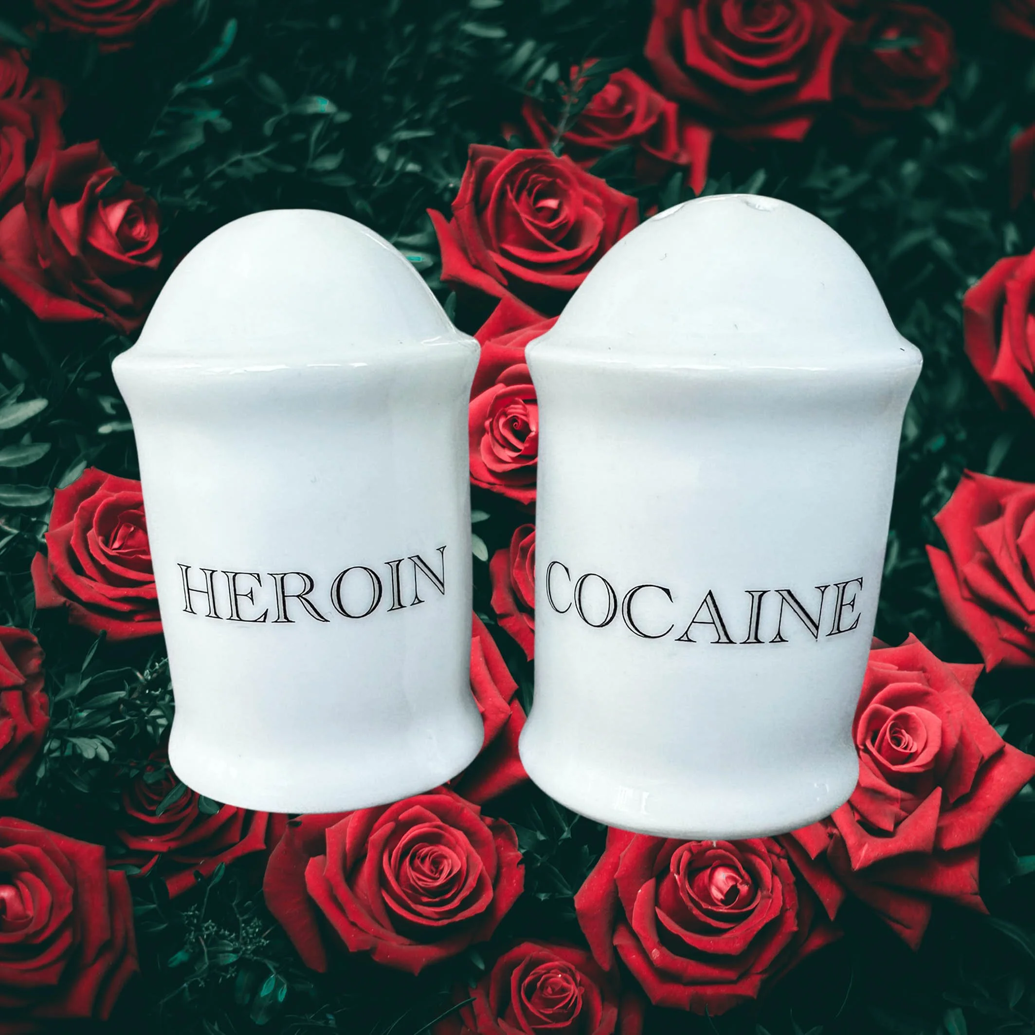 White salt and pepper shakers with the words “heroin” and “cocaine” in black cursive writing