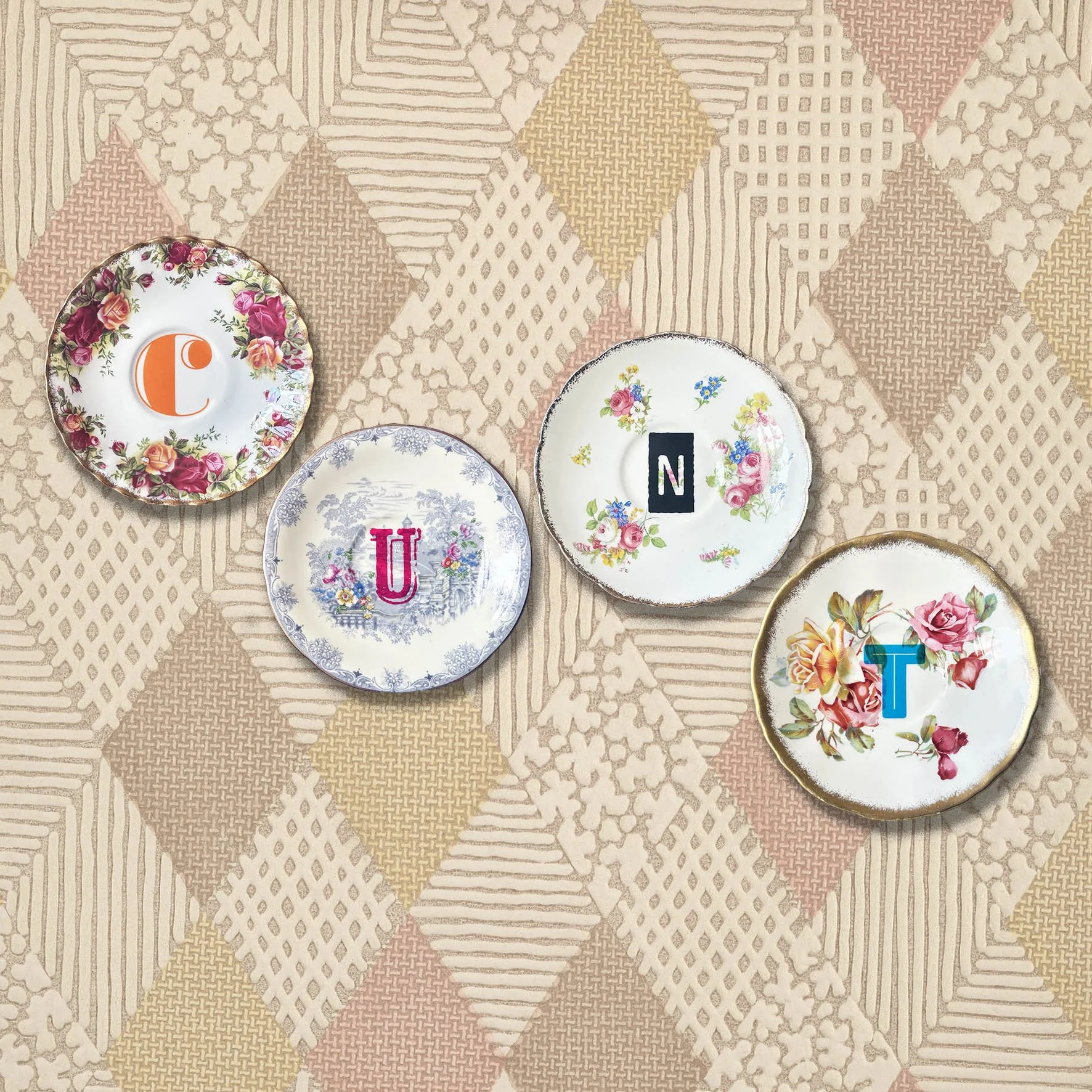 A set of vintage saucers spelling out the word “cunt” in colourful lettering