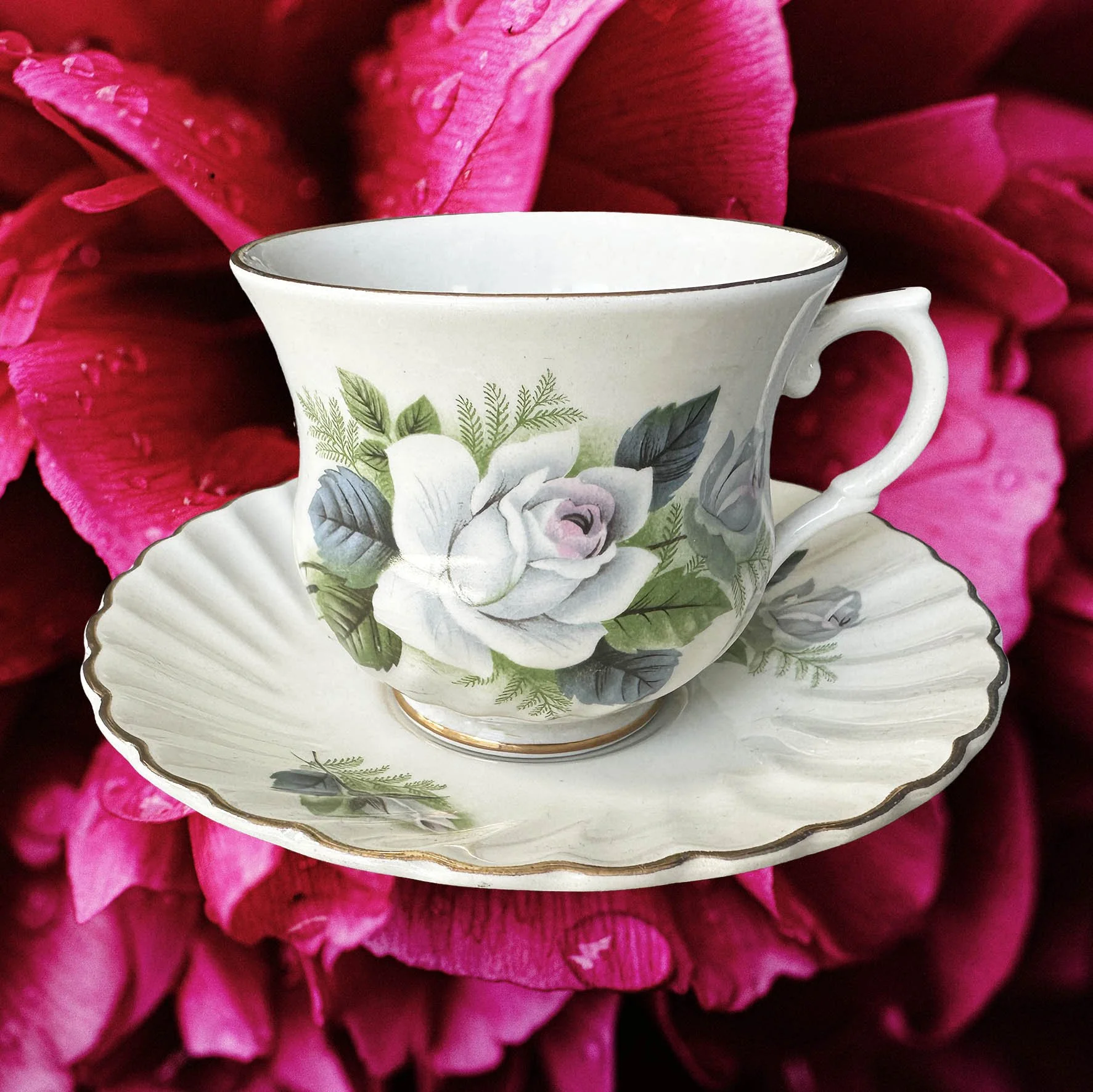 A vintage tea cup with a blue floral design and the words "maybe swearing will help" in black writing