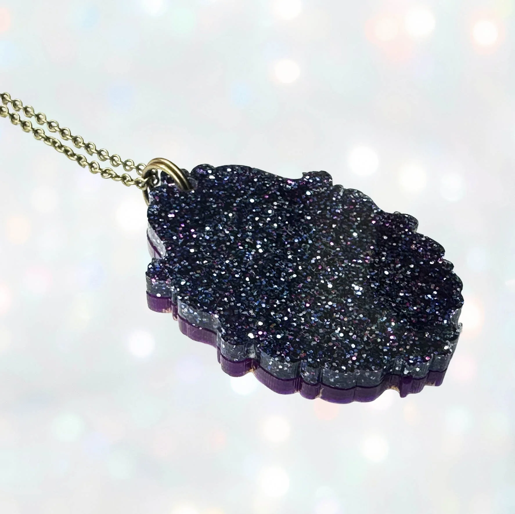 A purple, pink and gold laser cut acrylic cameo style necklace featuring a silhouette