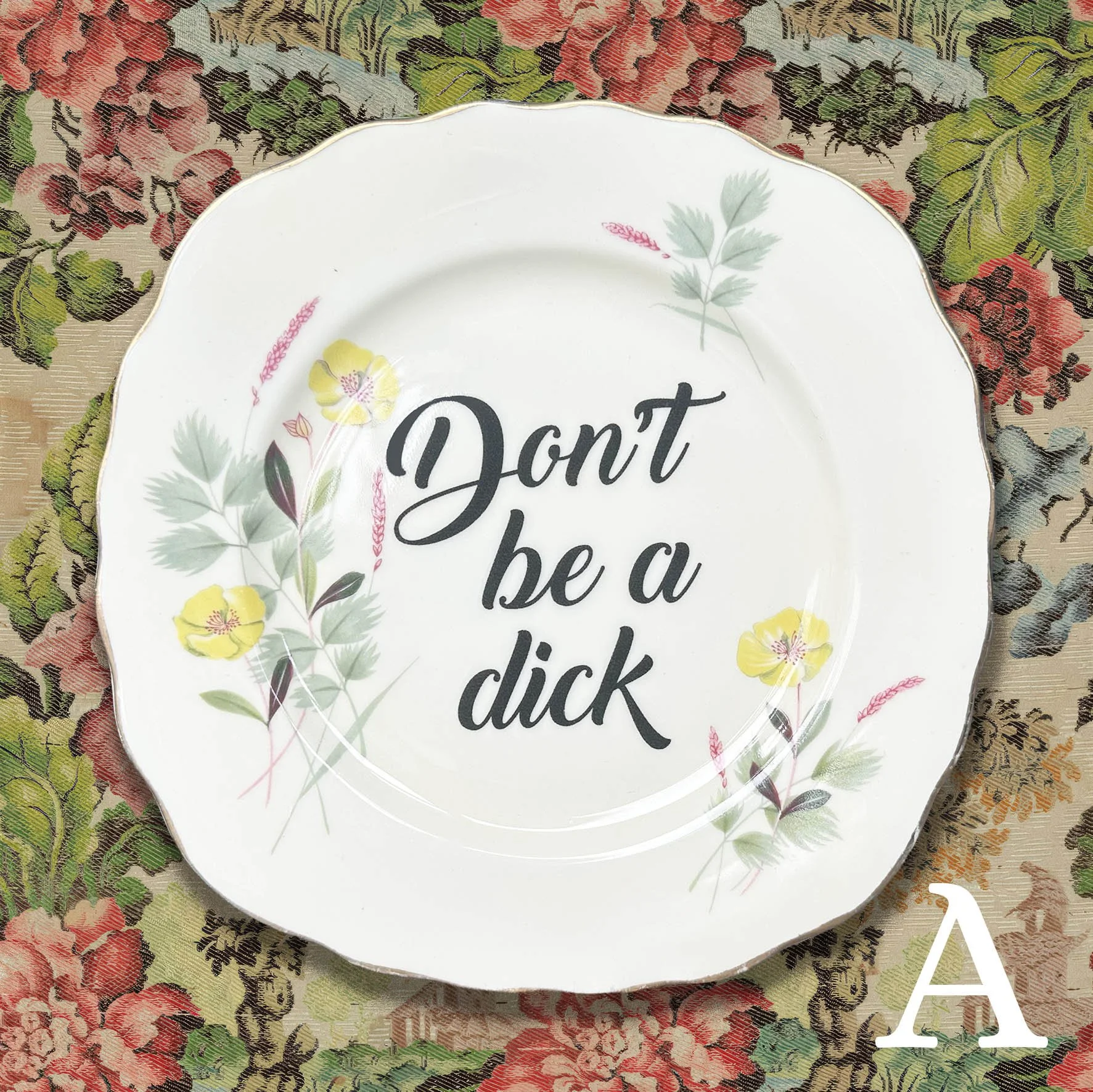 plate A: a vintage plate with a blue and yellow floral design with “don’t be a dick” in black writing