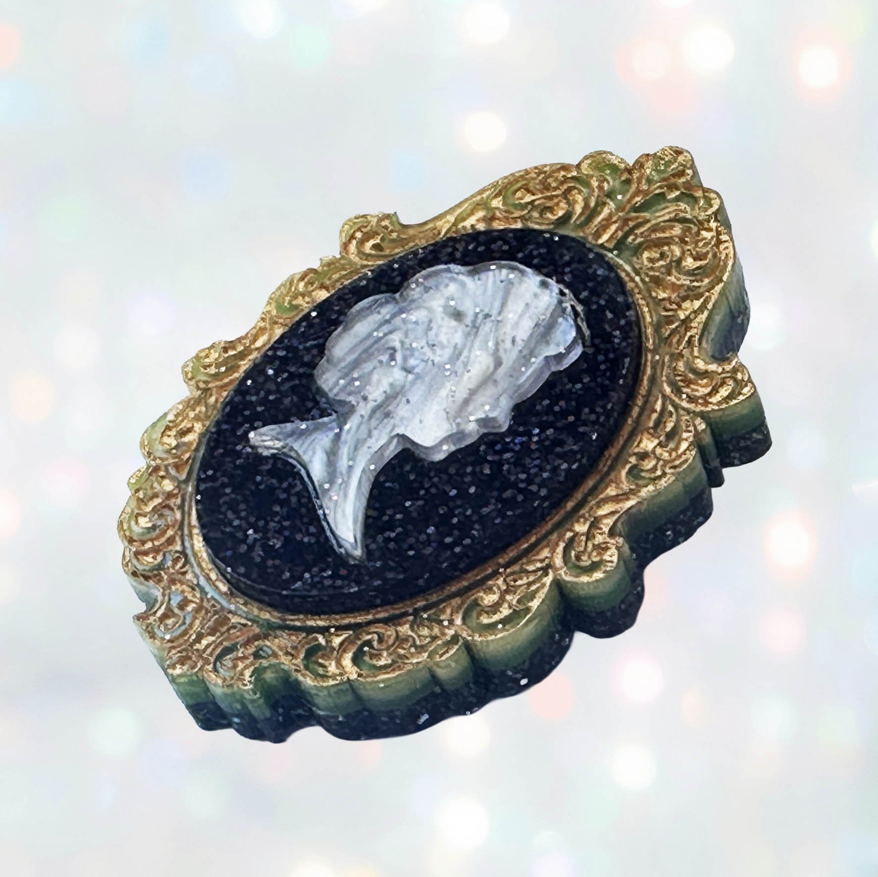 A laser cut green gold and black acrylic cameo style brooch featuring a silhouette