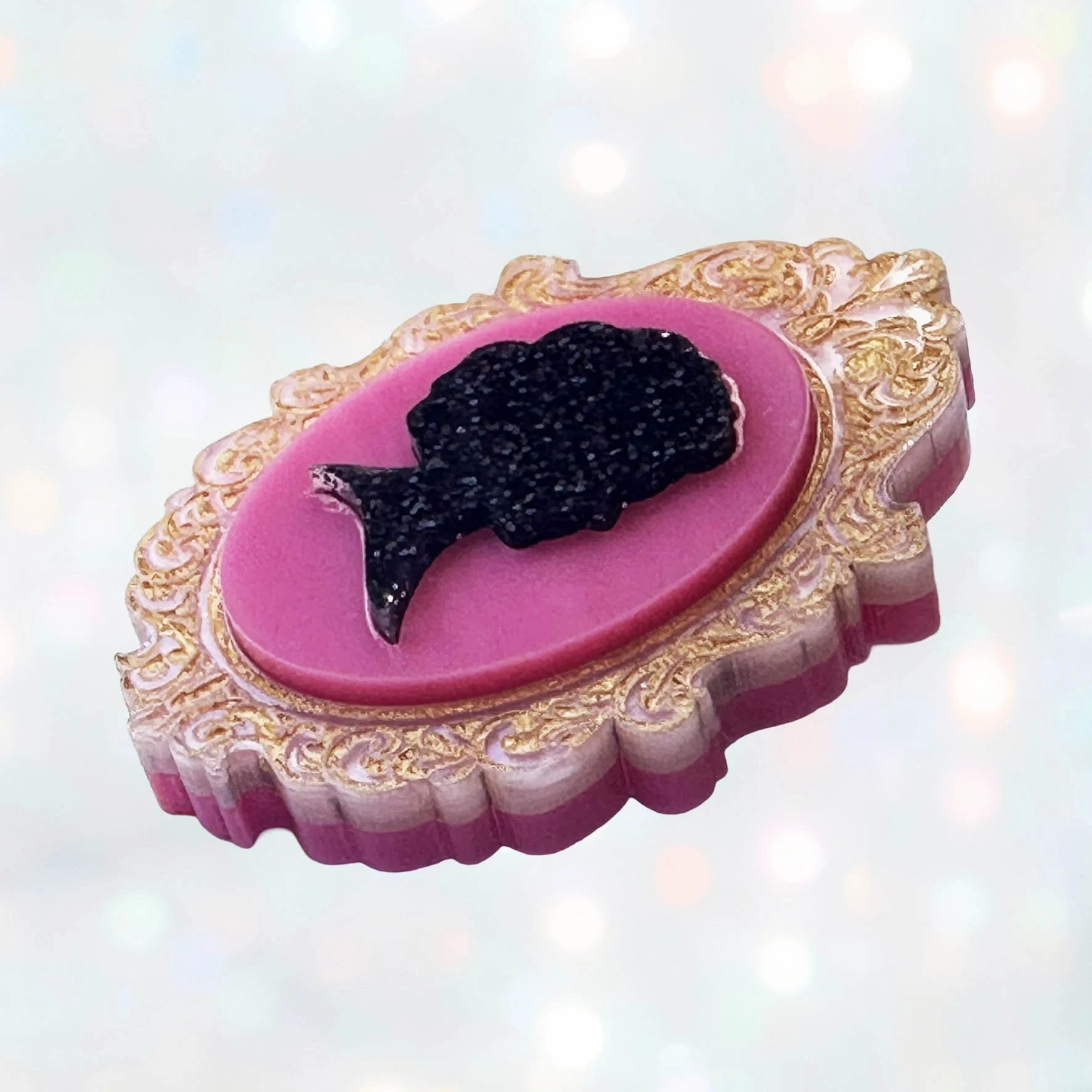 A pink, black and gold glitter laser cut acrylic cameo style brooch featuring a silhouette