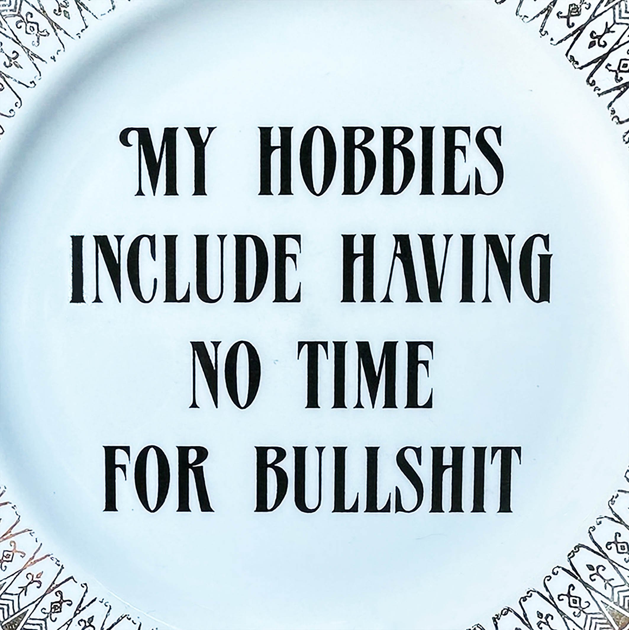 Vintage plate with a dark red and gold border, the lettering “my hobbies include having to time for bullshit” in black, decorative wall plate