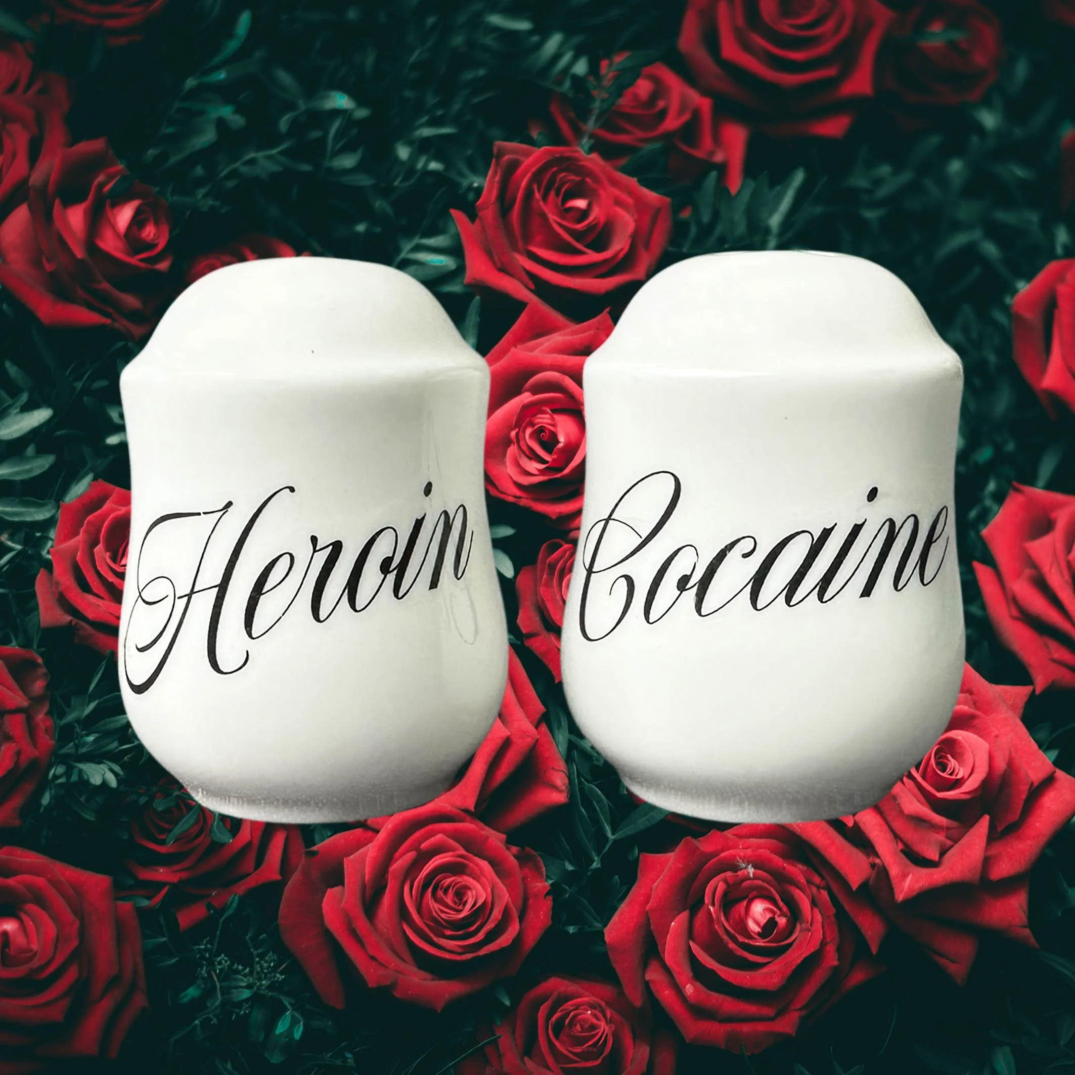 White salt and pepper shakers with the words “heroin” and “cocaine” in black cursive writing