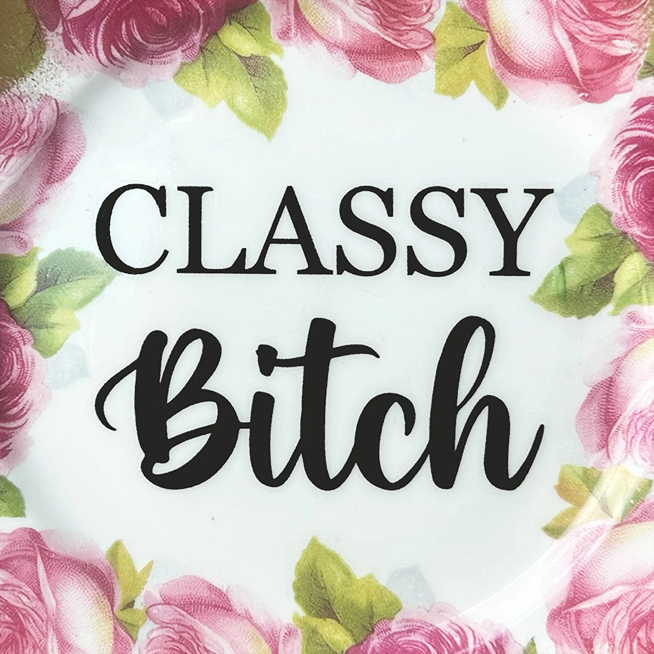 A vintage decorative wall plate with the words "classy bitch" in black writing
