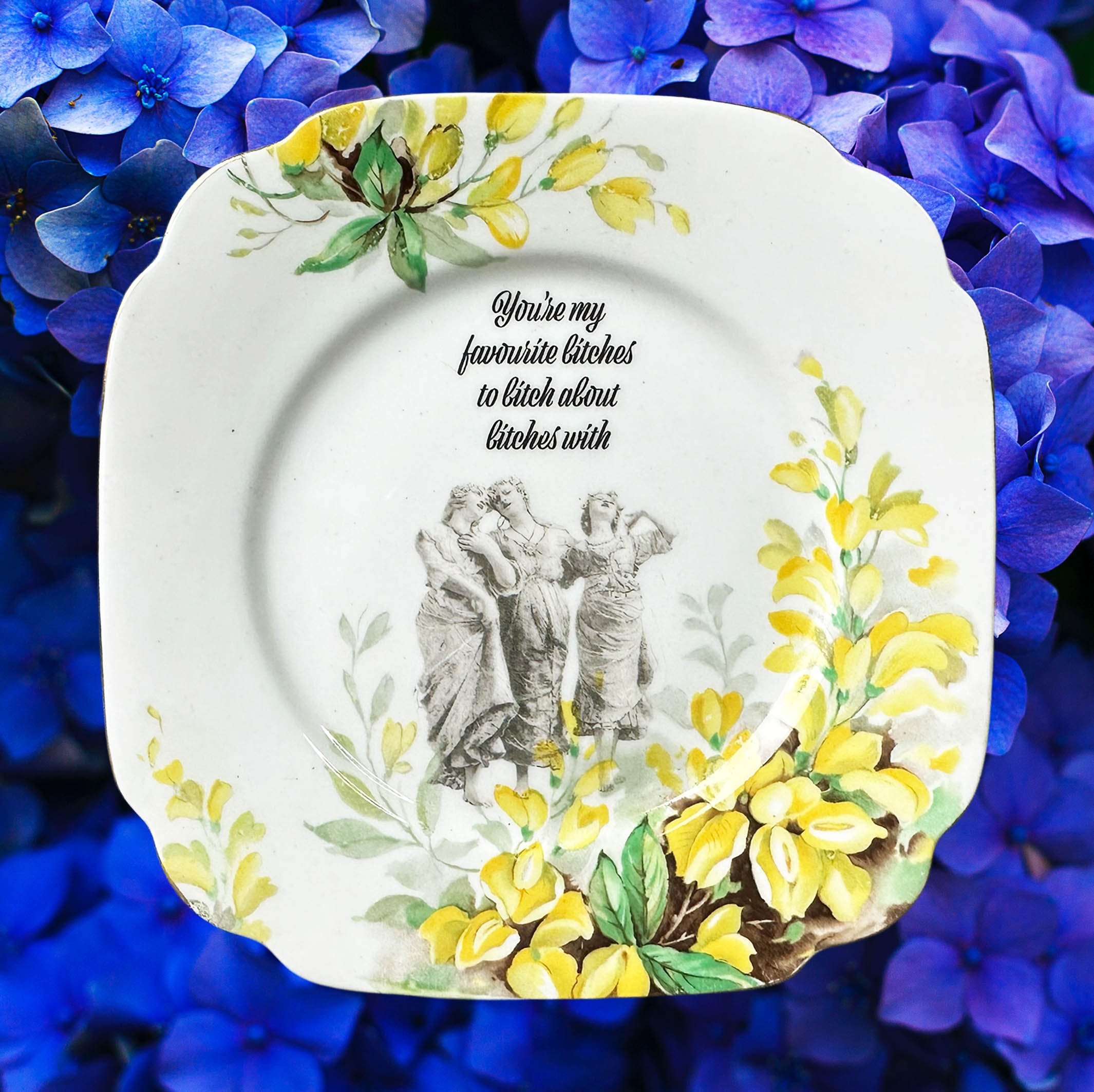 Vintage plate with yellow flowers and the image of three women, black writing “you’re my favourite bitches to bitch about bitches with”