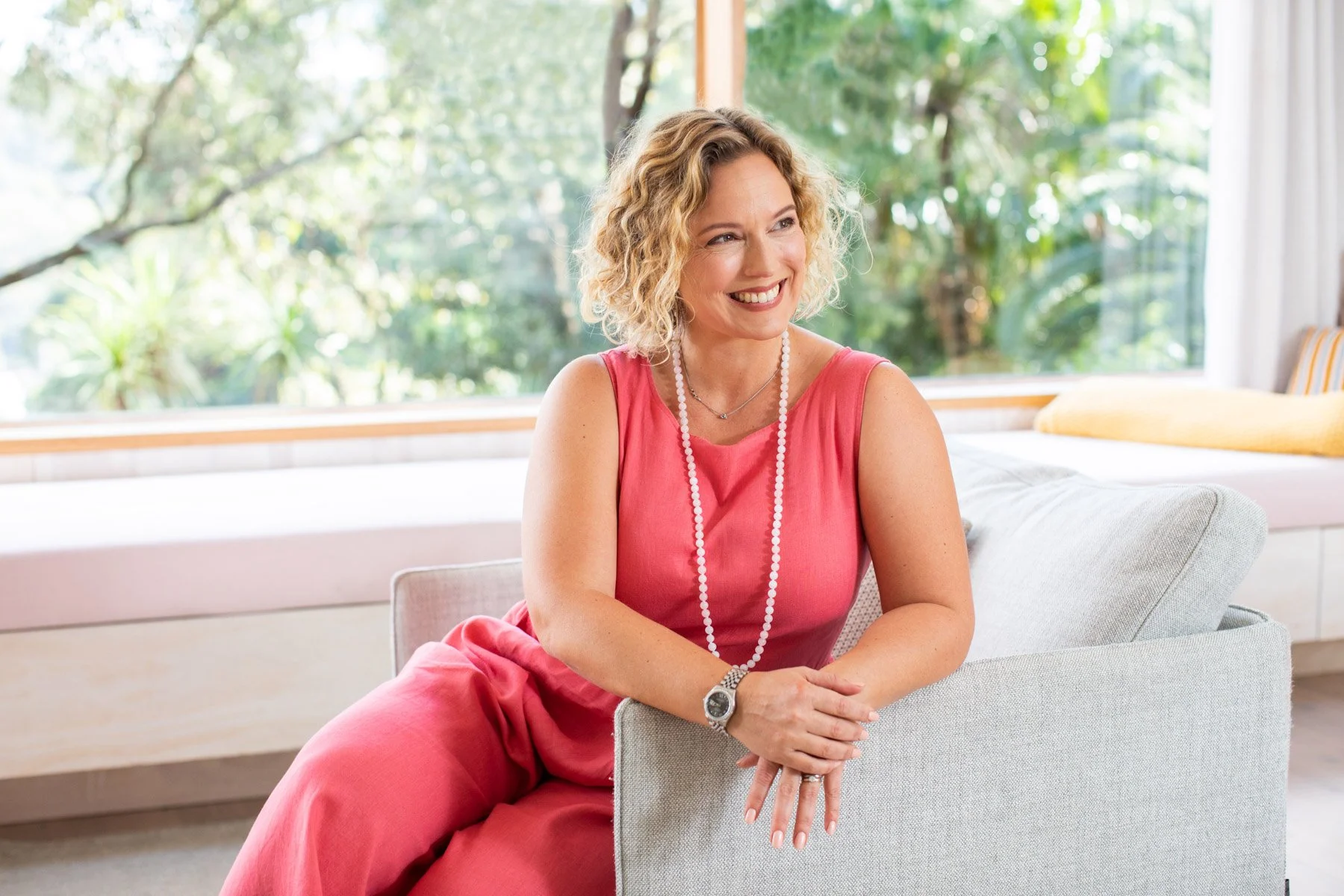 Kristina Rasmussen, Naturopath and HPV expert smiling warmly in a pink jumpsuit. Image by Sydney brand photographer Heist Creative.