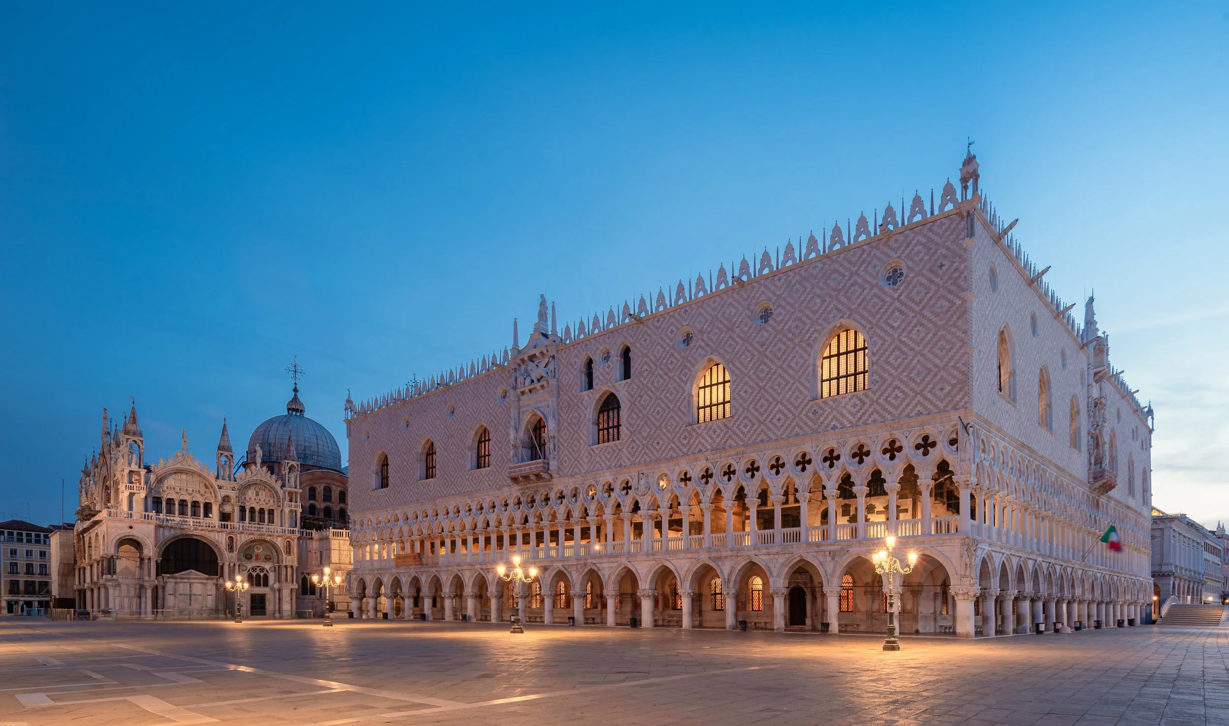 Palazzo Ducale di Venezia illuminato di notte, con dettagli architettonici gotici e vetrate