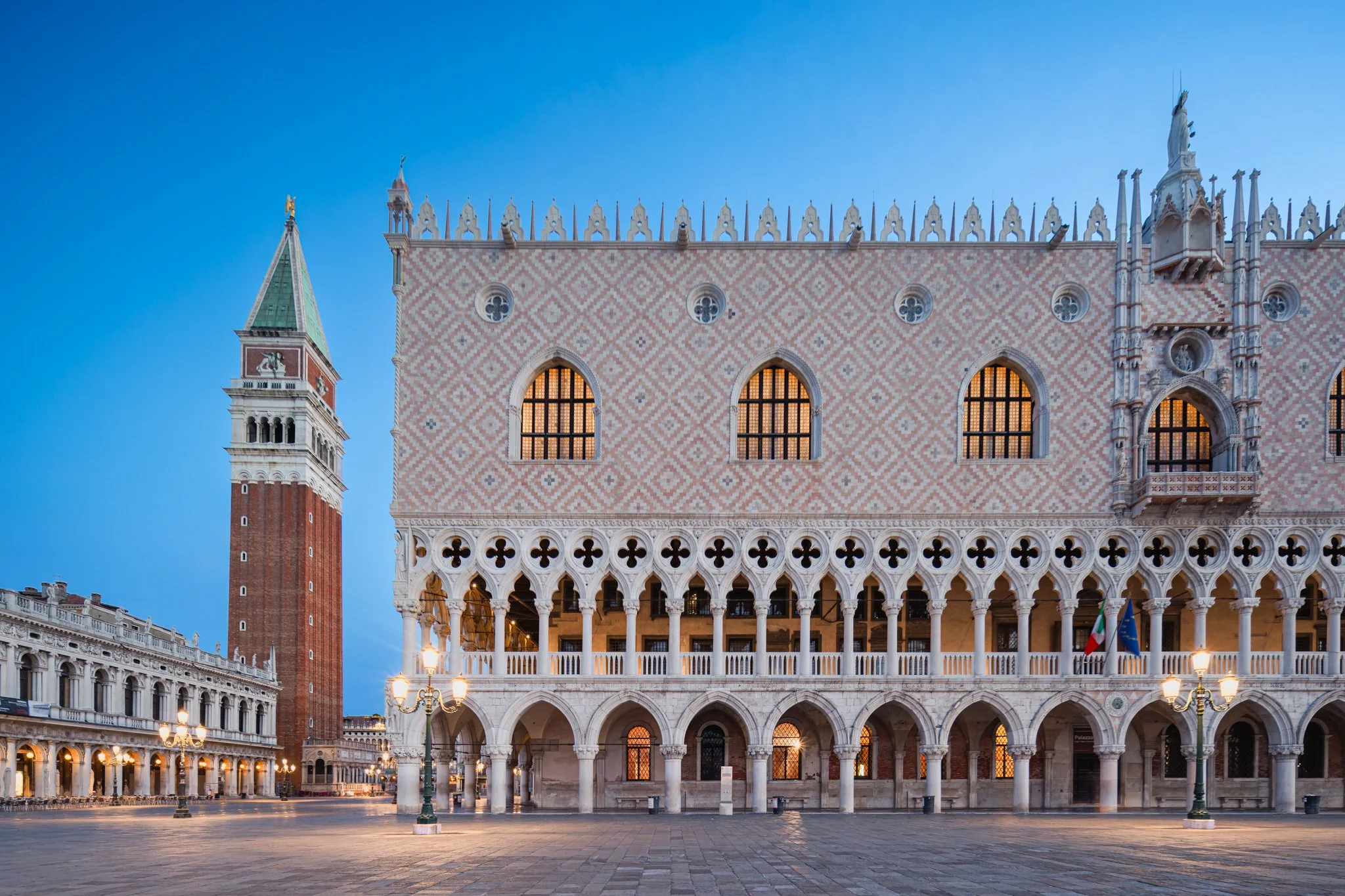 Veduta della piazza di San Marco a Venezia con il Palazzo Ducale e la Torre dell'Orologio, al tramonto.