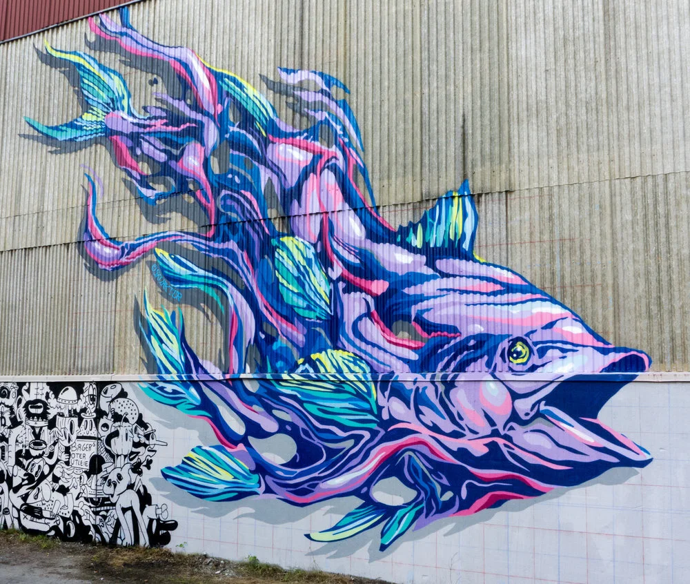 Colorful mural of a fish with flowing fins and tail, painted on a large wall.