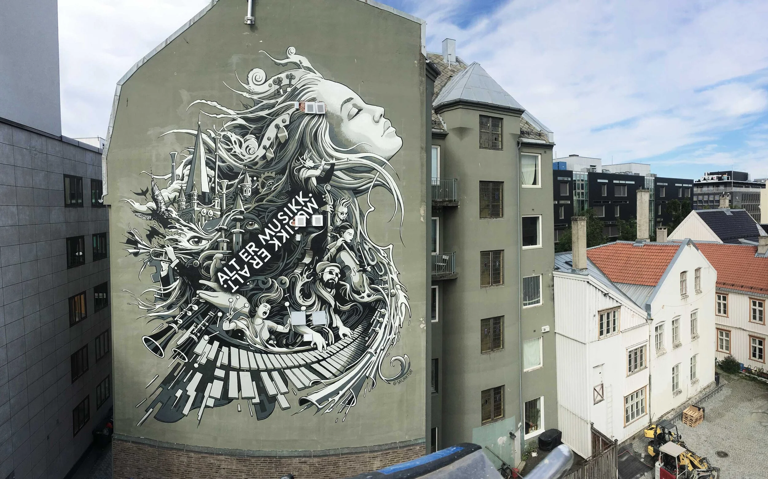 A large mural of a woman with flowing hair and closed eyes, surrounded by musical instruments and notes, painted on the side of a building in an urban setting.