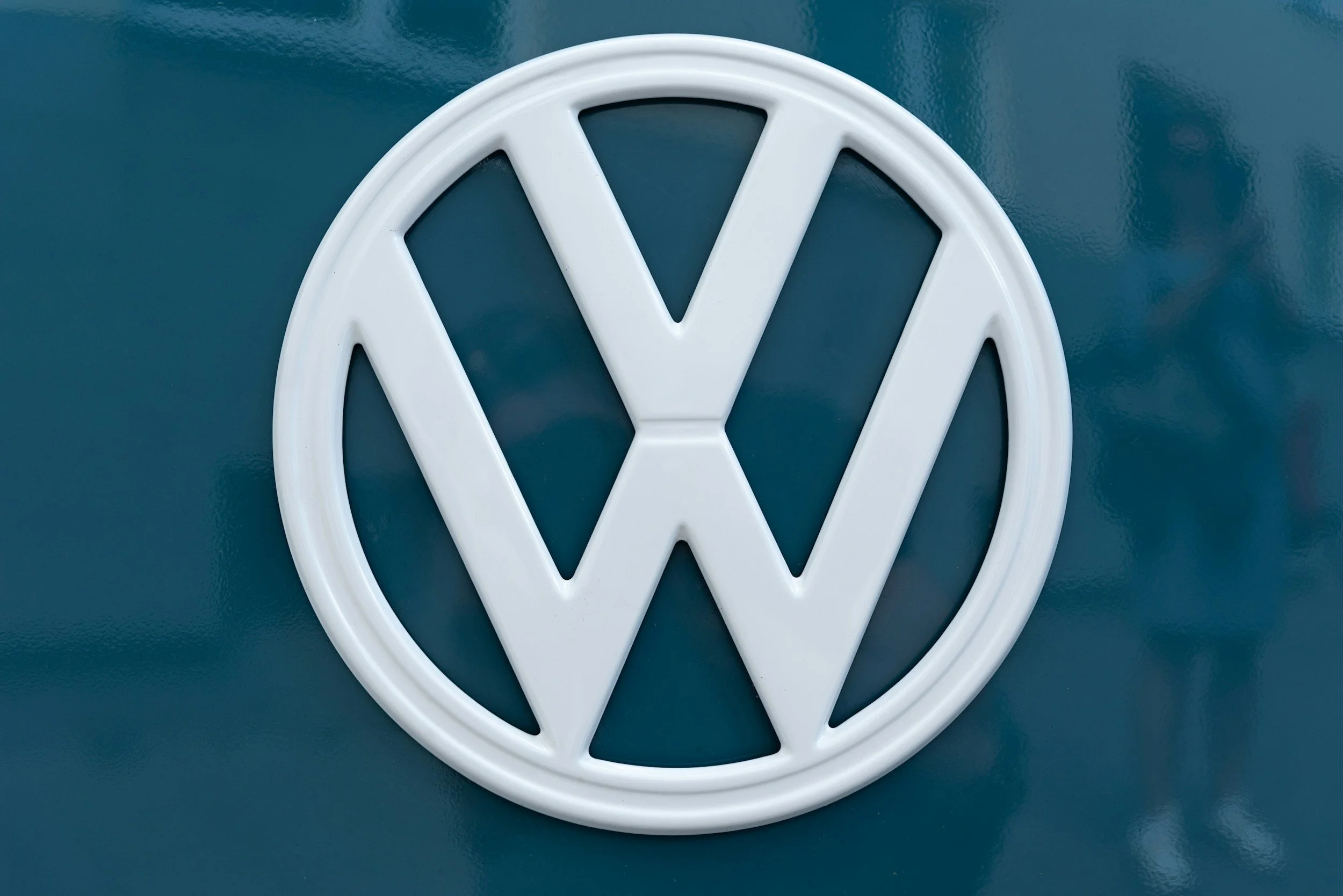 White Volkswagen logo on teal background.