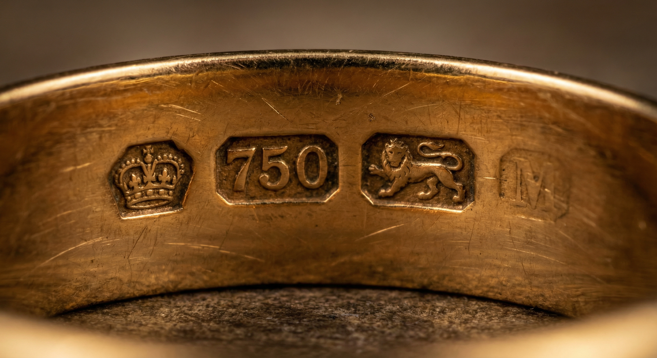 Close-up of UK gold hallmarks on antique jewellery showing assay office mark, carat stamp, and maker's mark