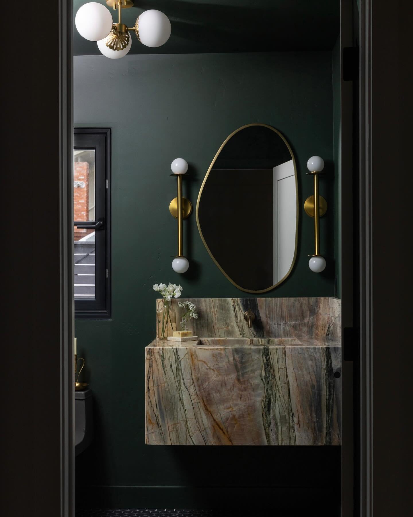 Take a peek into one of our all-time favorite powder rooms. The custom vanity and integrated sink were fabricated from a slab of Michelangelo quartzite, selected for its dramatic veining and gorgeous orange &amp; green tones. The walls are painted Fa