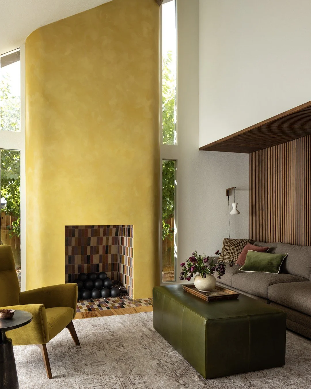 Just off the burgundy kitchen, this theater room mixes warmth and function with a softly curved fireplace finished in a faux plaster paint by @sunnydispostudio, paired with walnut paneling and a hidden drop-down projector screen for movie nights done