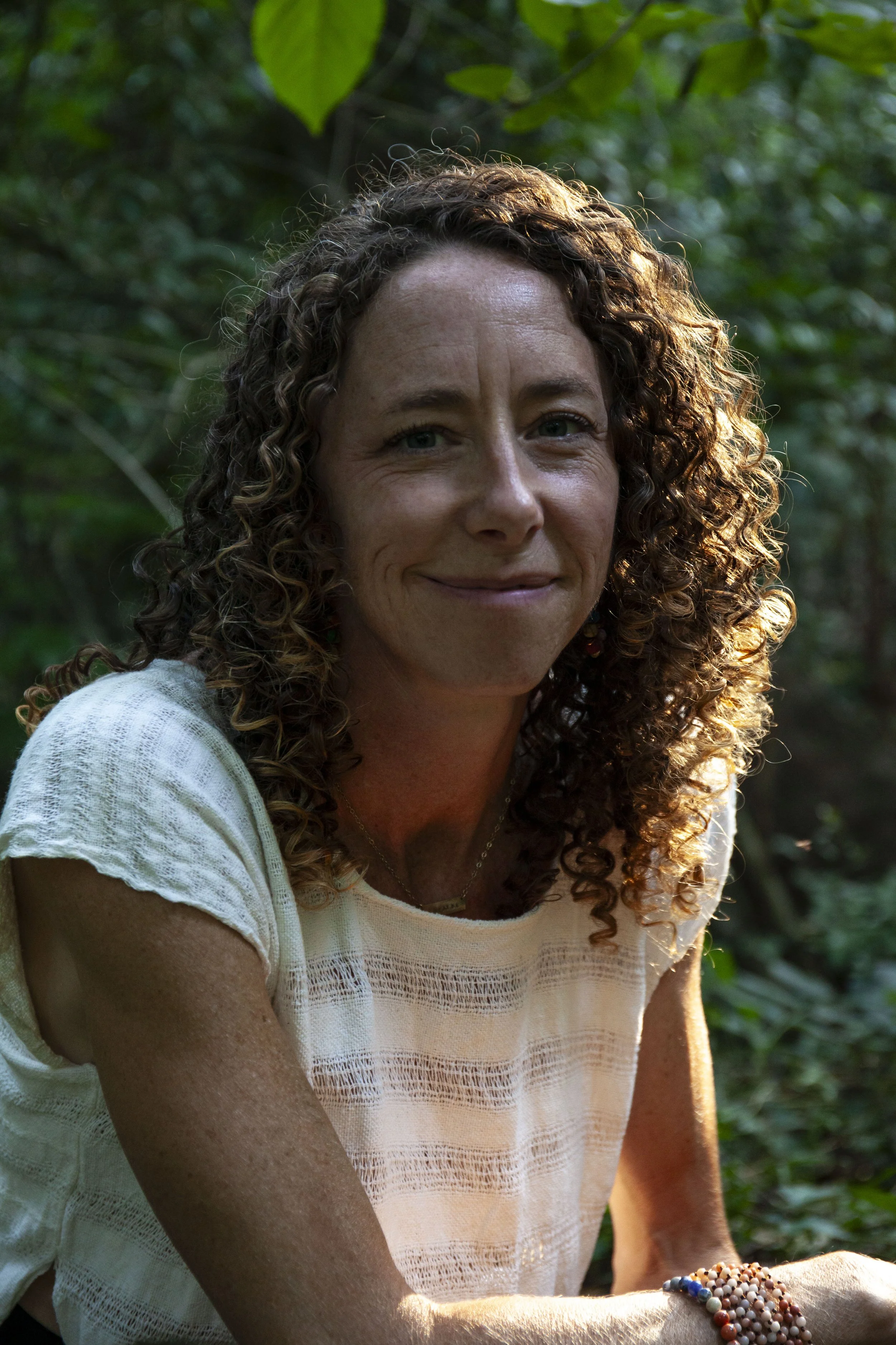 Female outside curly brown hair soft smile