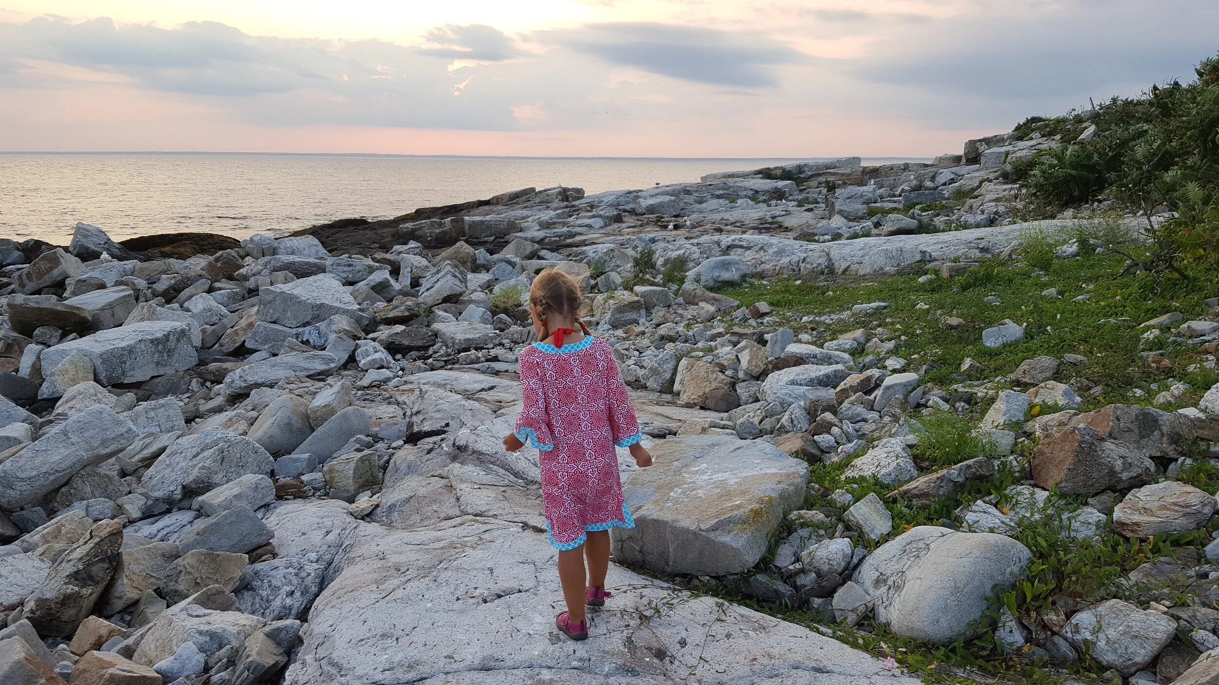 A child walks on rocks near the ocean