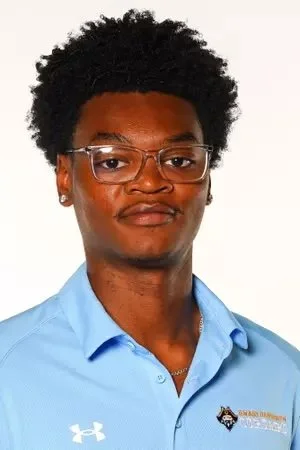 Man in a blue polo shirt with a track and field logo, posing for a portrait against a plain background.
