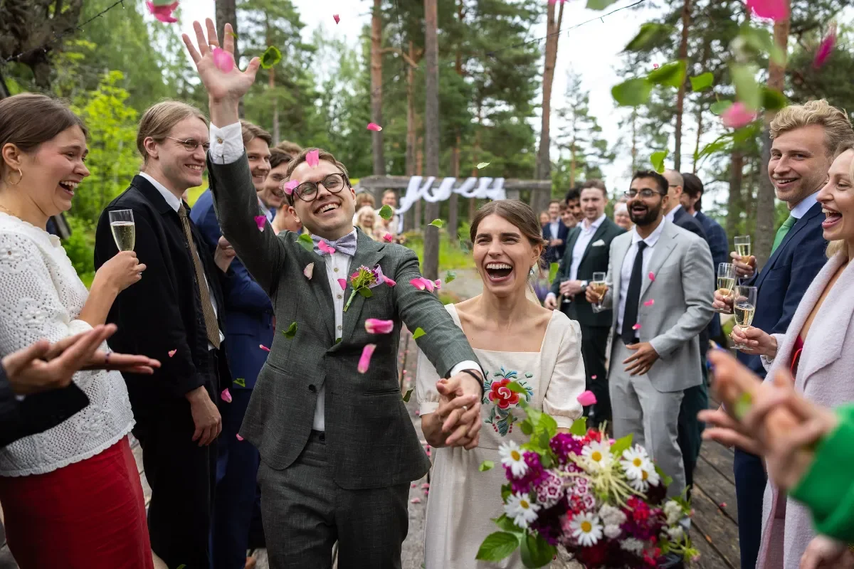 Hääpari saapuu juhlapaikalle ja ruusun terälehtiä satelee ilmaan