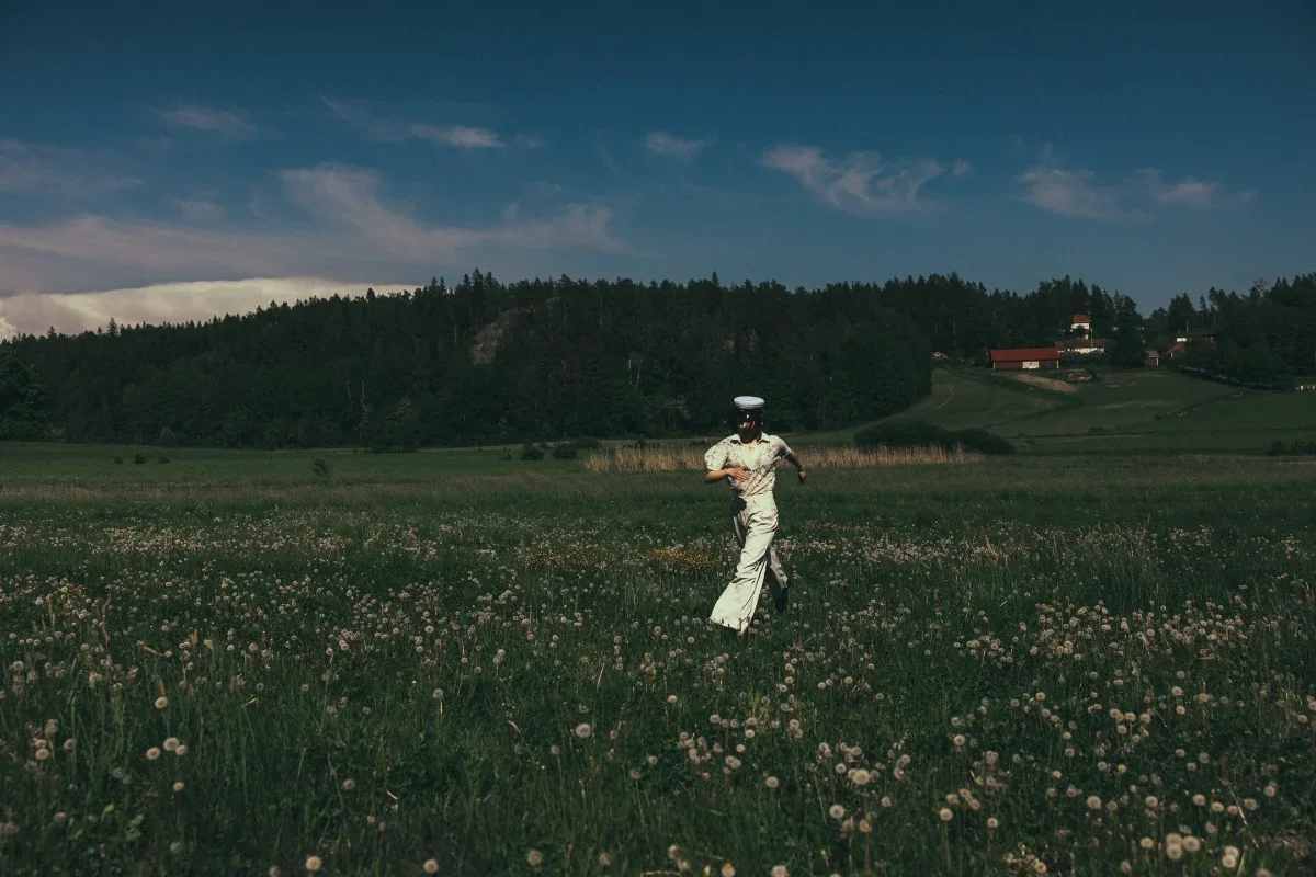 Vastavalmistunut ylioppilas juoksee vihreällä nurmikolla.