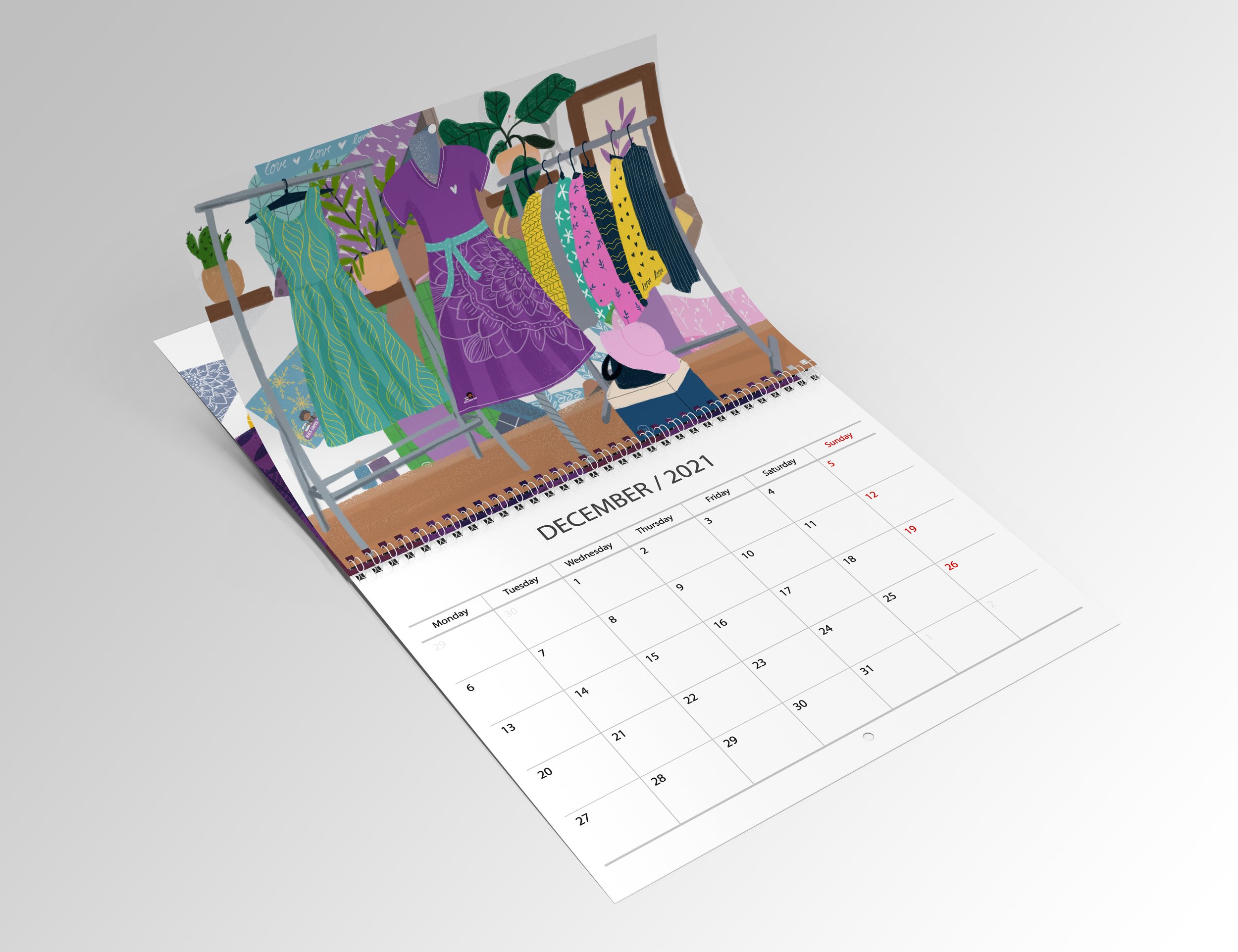 Open desk calendar showing December 2021, featuring a vibrant illustration of colorful dresses hanging on a rack with plants in the background.